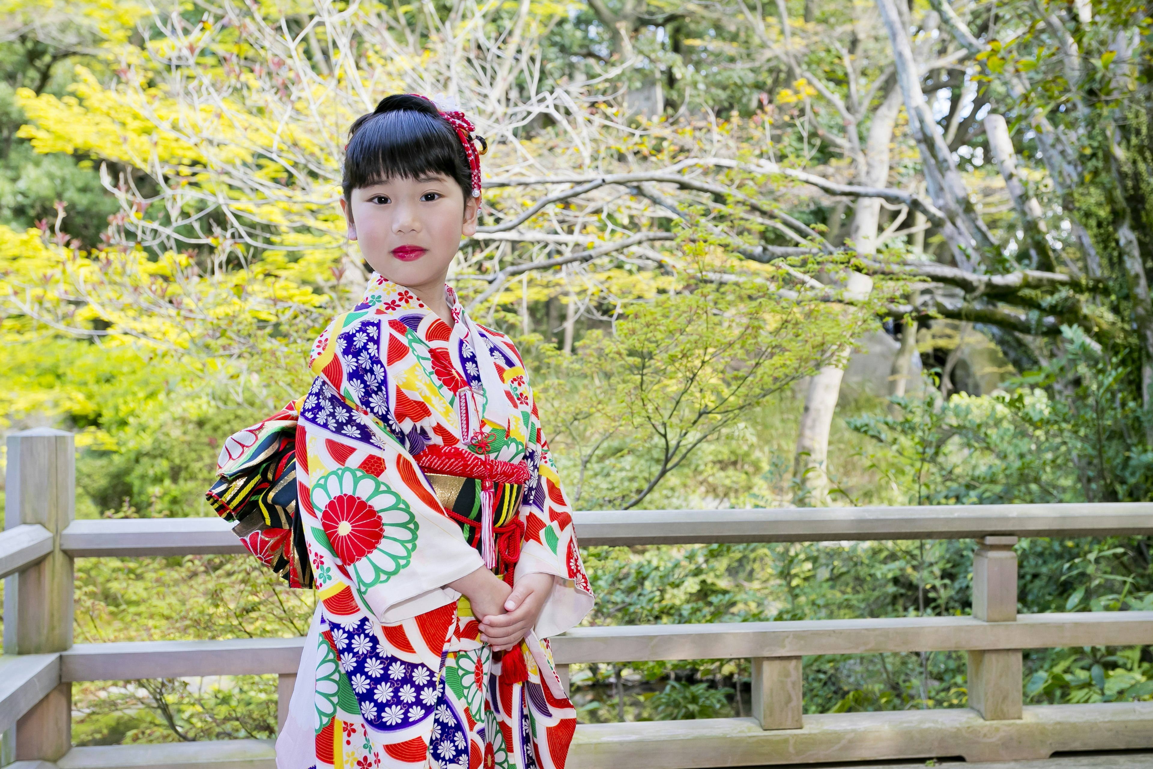 Một người phụ nữ trong bộ kimono đầy màu sắc tạo dáng trong khung cảnh thiên nhiên