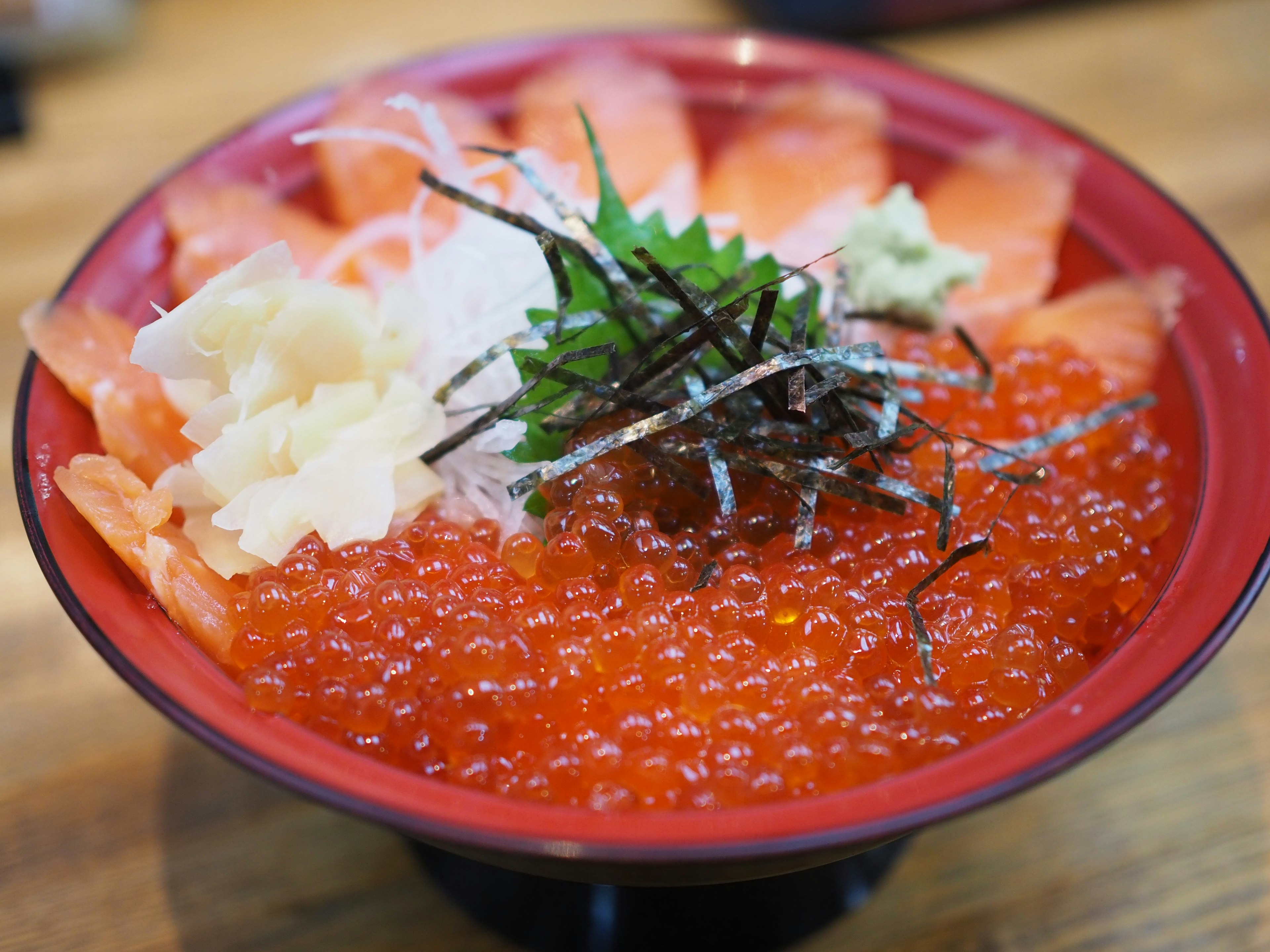 Red bowl filled with salmon sashimi and salmon roe