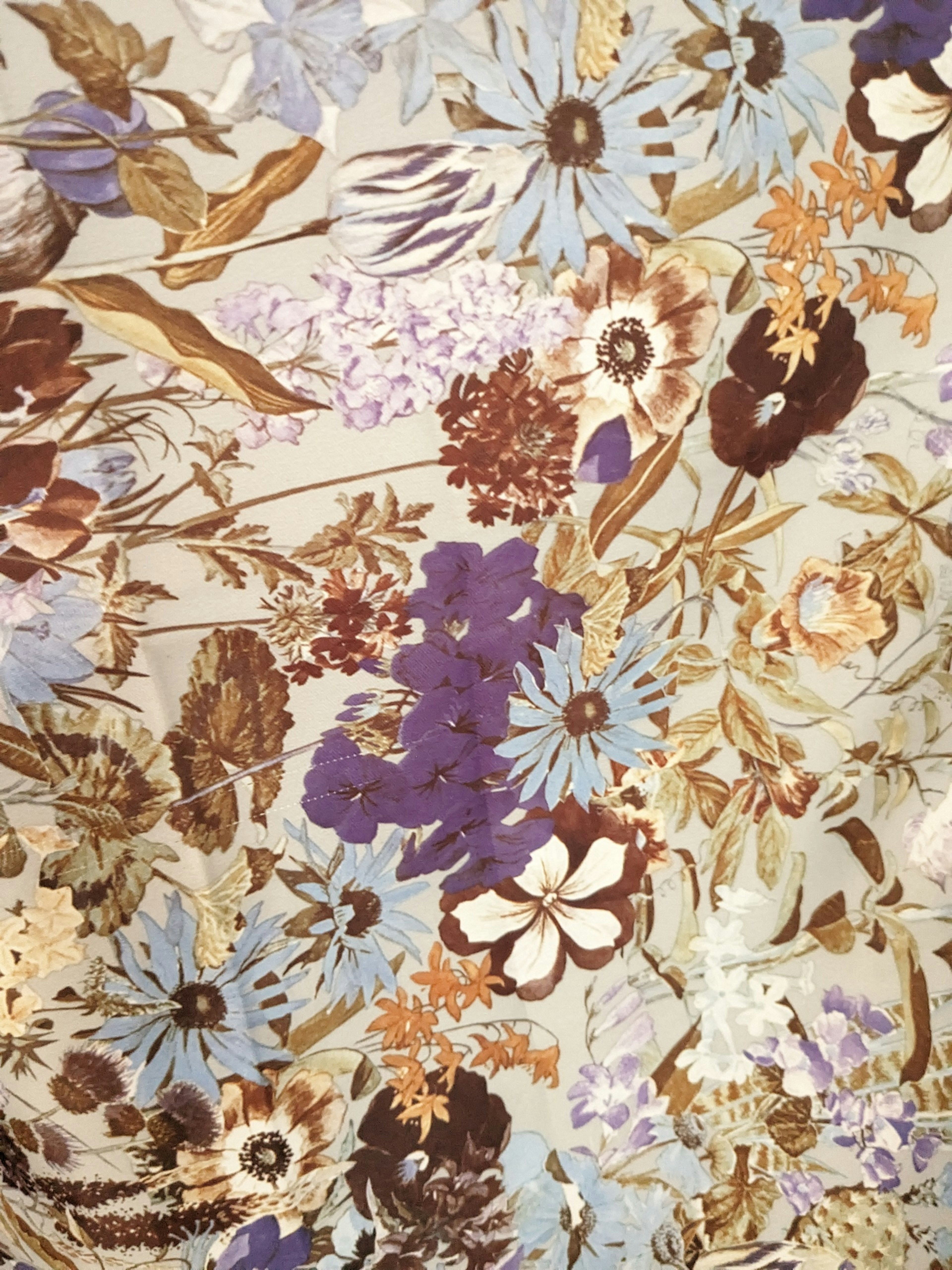 Tissu floral avec des motifs de fleurs bleues, violettes et brunes