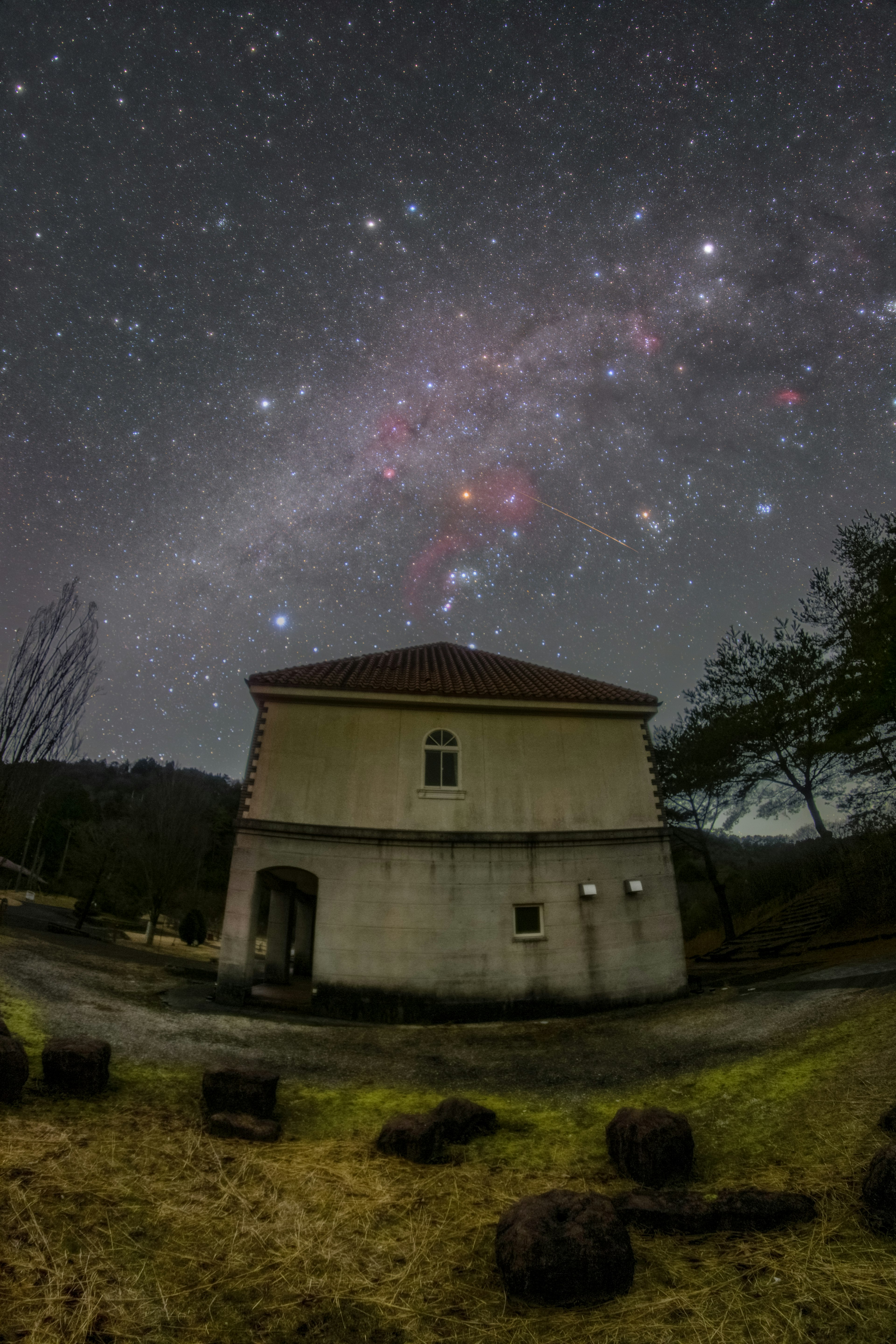 星空の下にある建物と周囲の自然が広がる夜景