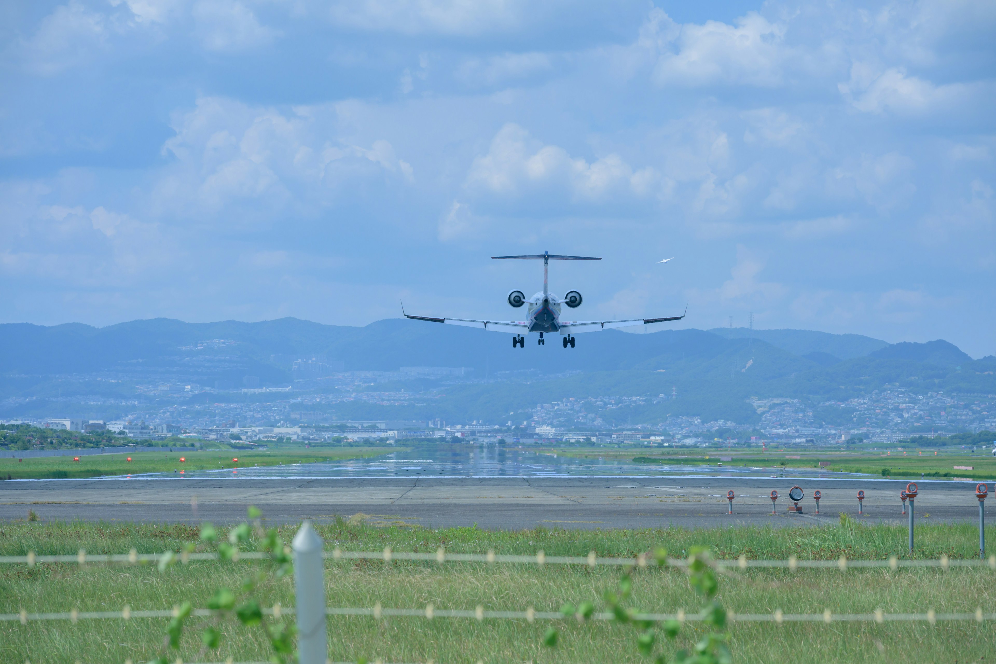 Pequeño jet aterrizando bajo un cielo azul con montañas al fondo