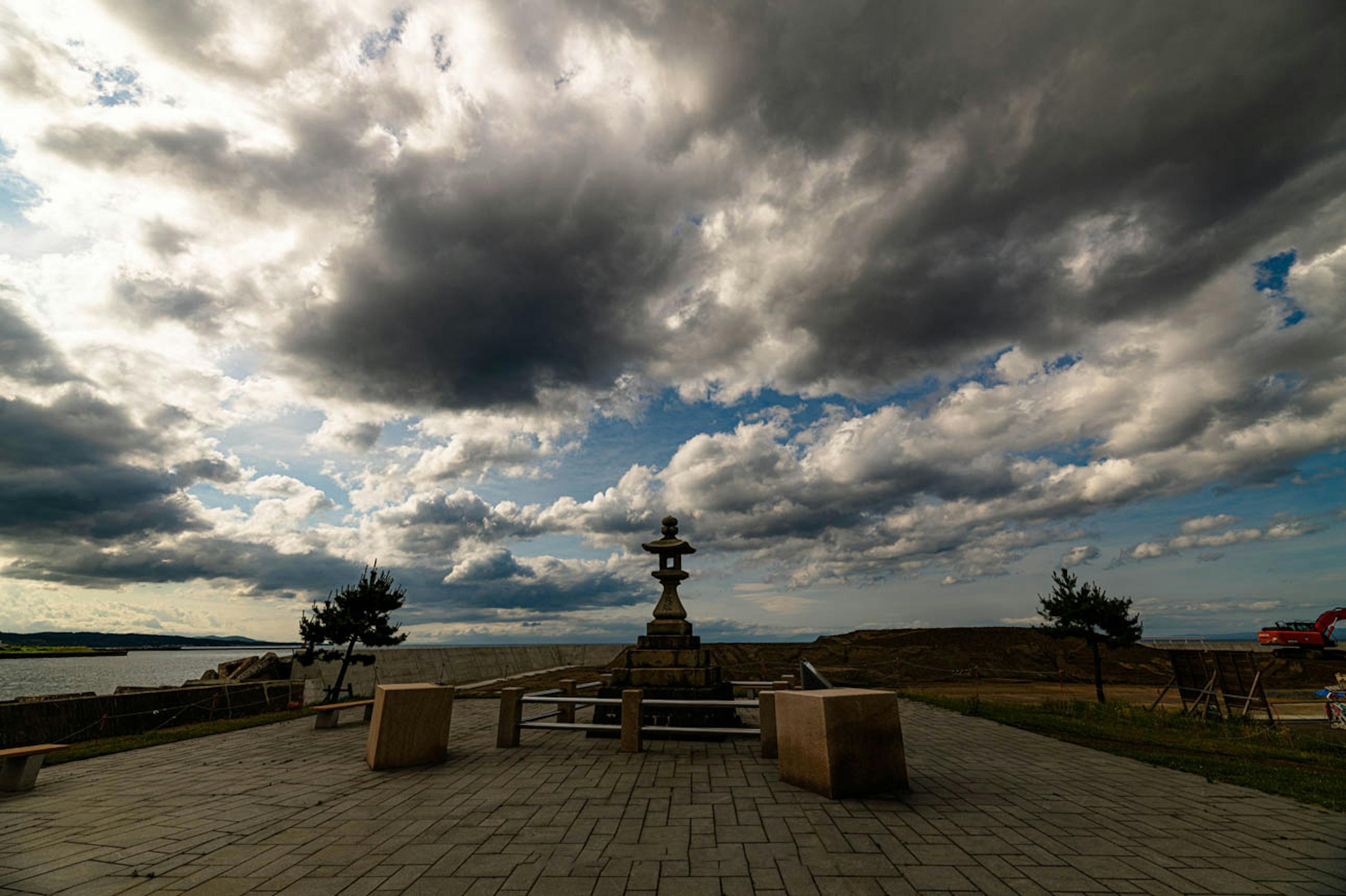 Paesaggio con fontana e panchine sotto un cielo vasto e nuvoloso