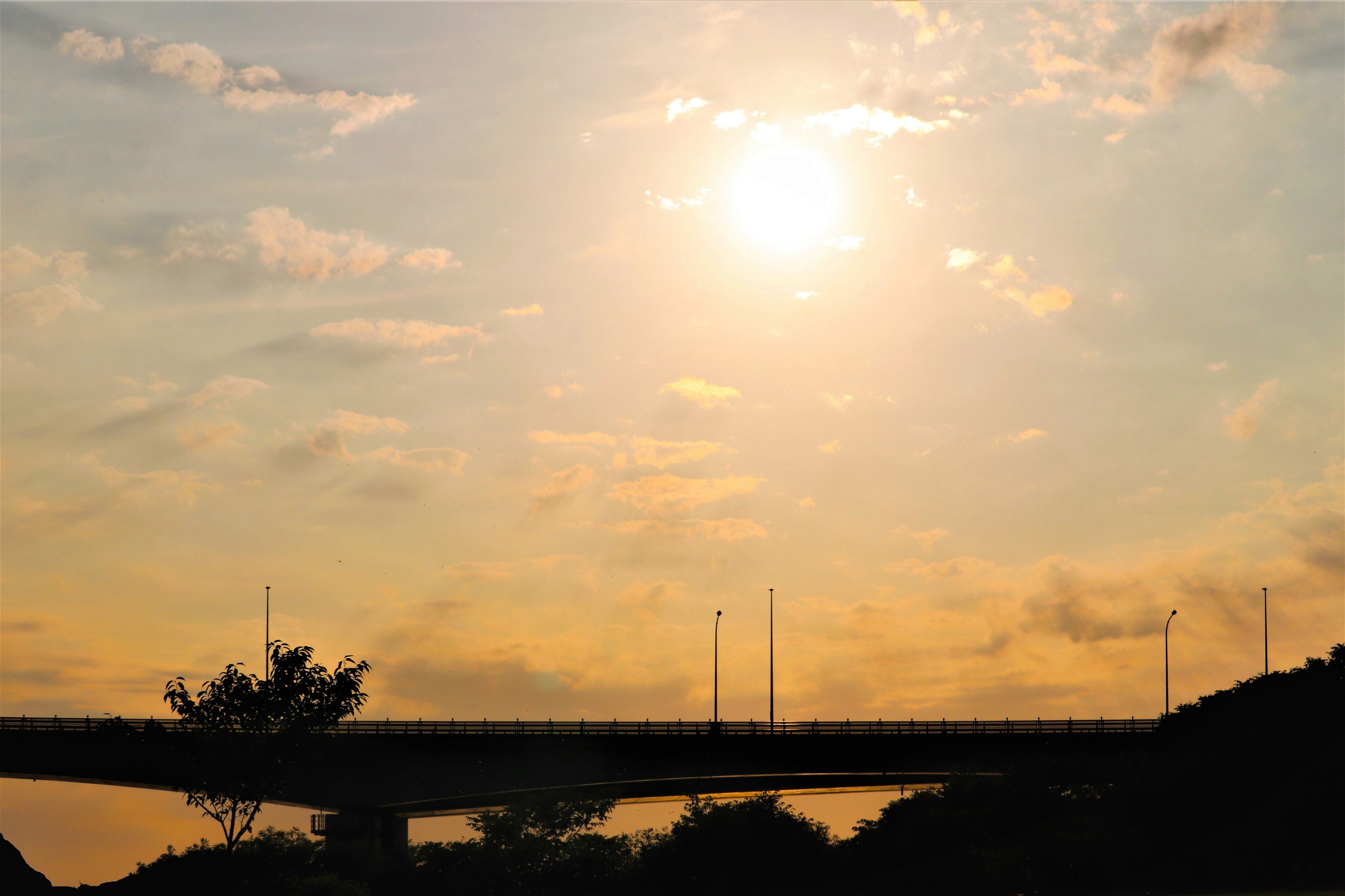 สะพานที่มีเงาอยู่ในท้องฟ้ายามพระอาทิตย์ตกพร้อมเมฆ