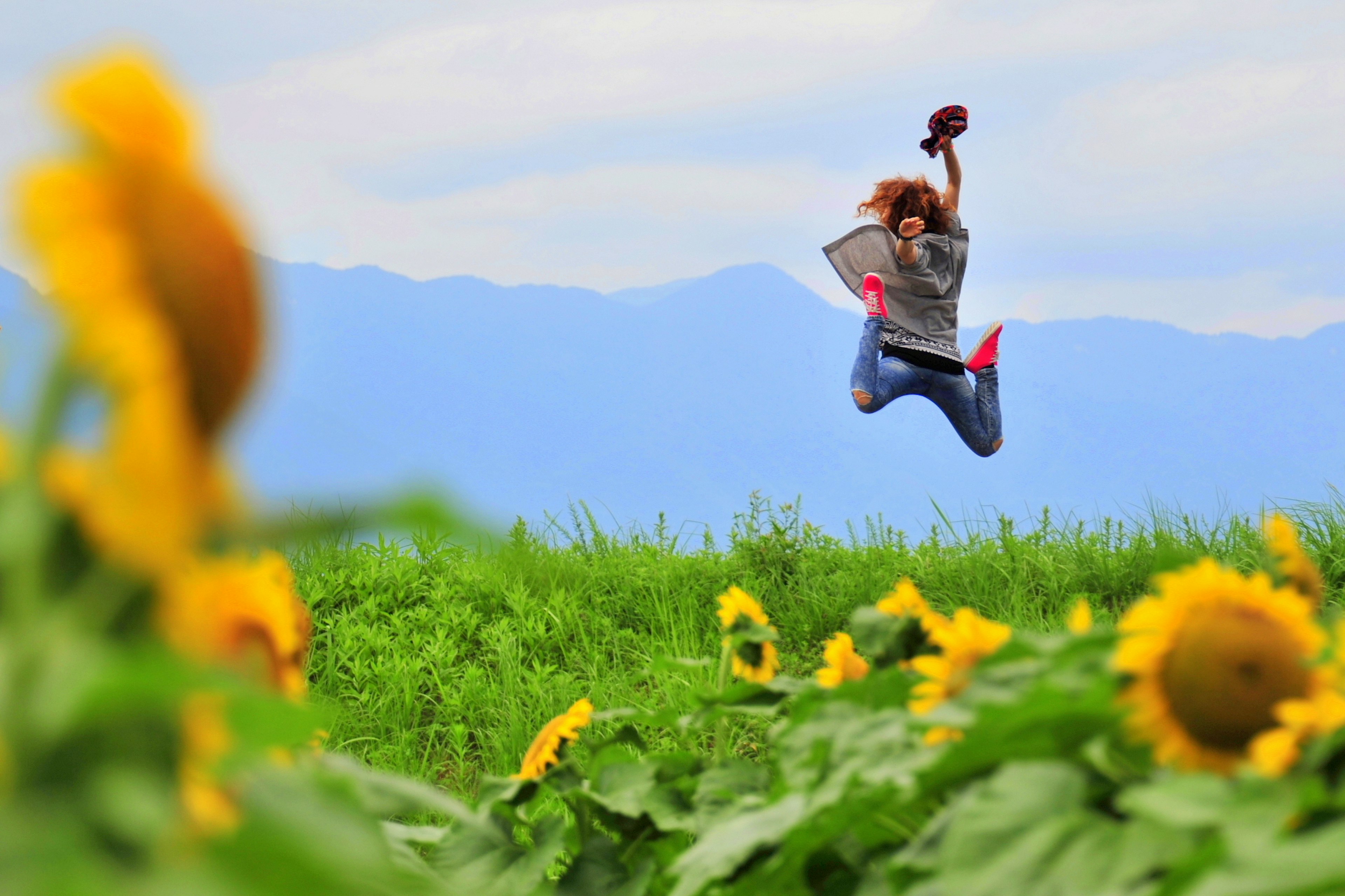 Una donna che salta gioiosamente in un campo di girasoli