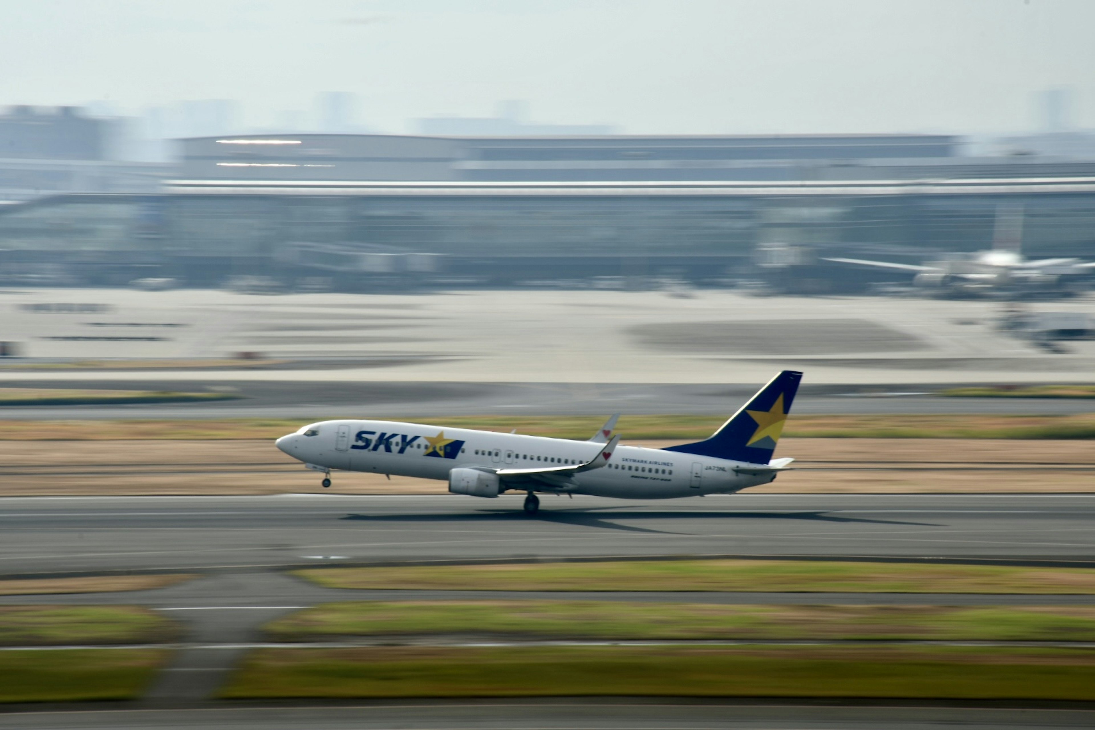 Flugzeug startet auf der Startbahn mit Flughafen im Hintergrund