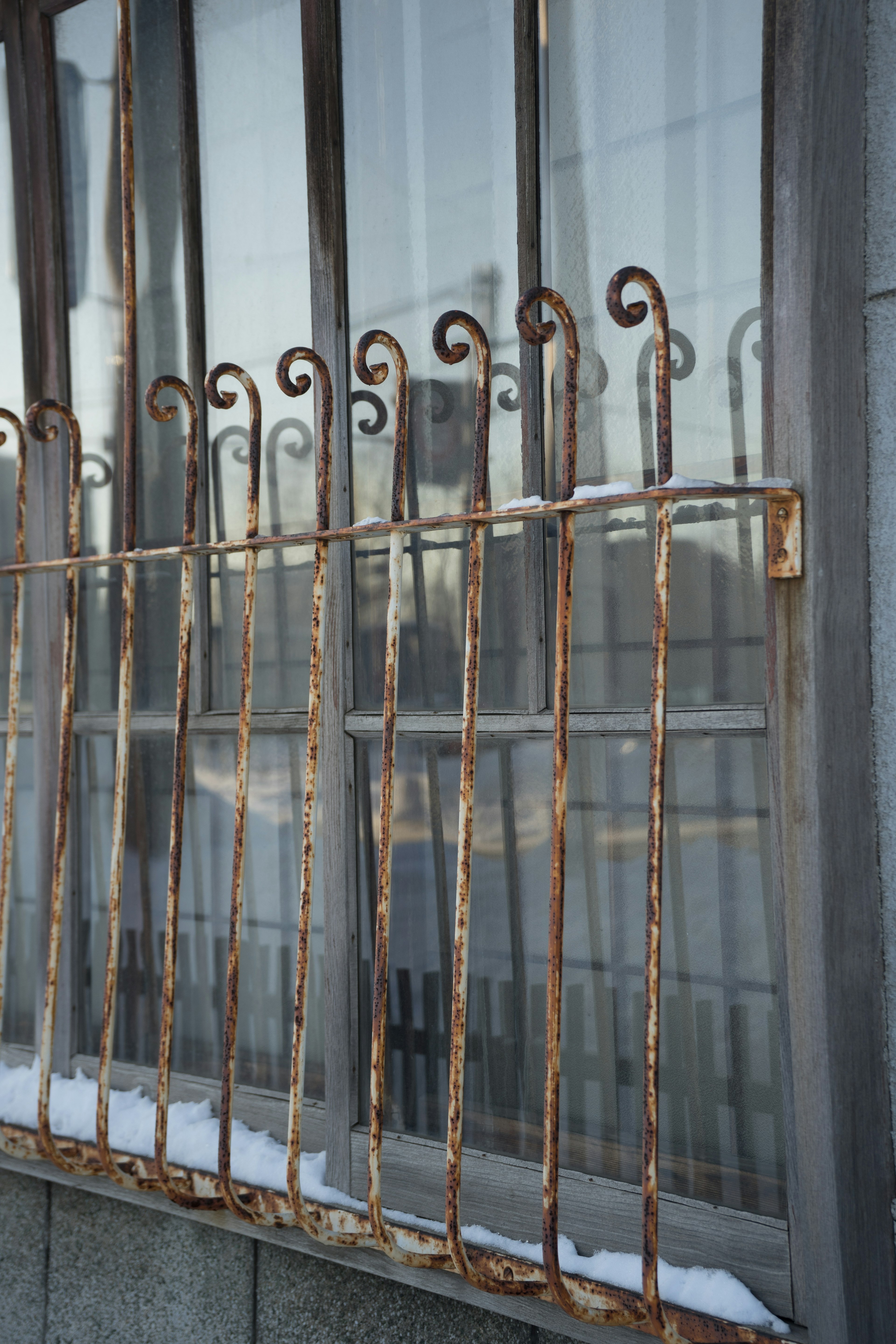 Photo of an old iron window grille featuring a rusty color and unique design