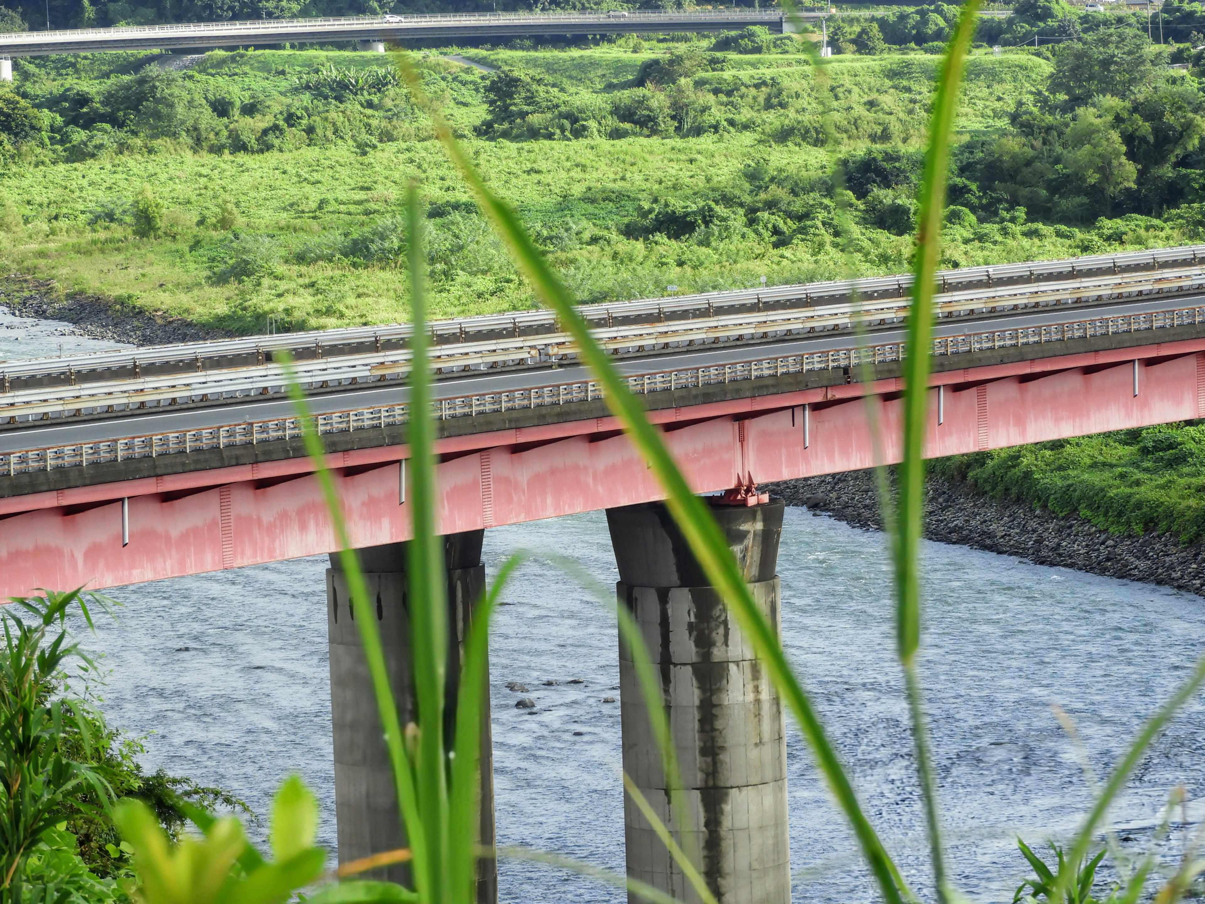 Eine rote Brücke über einen Fluss, umgeben von üppigem Grün