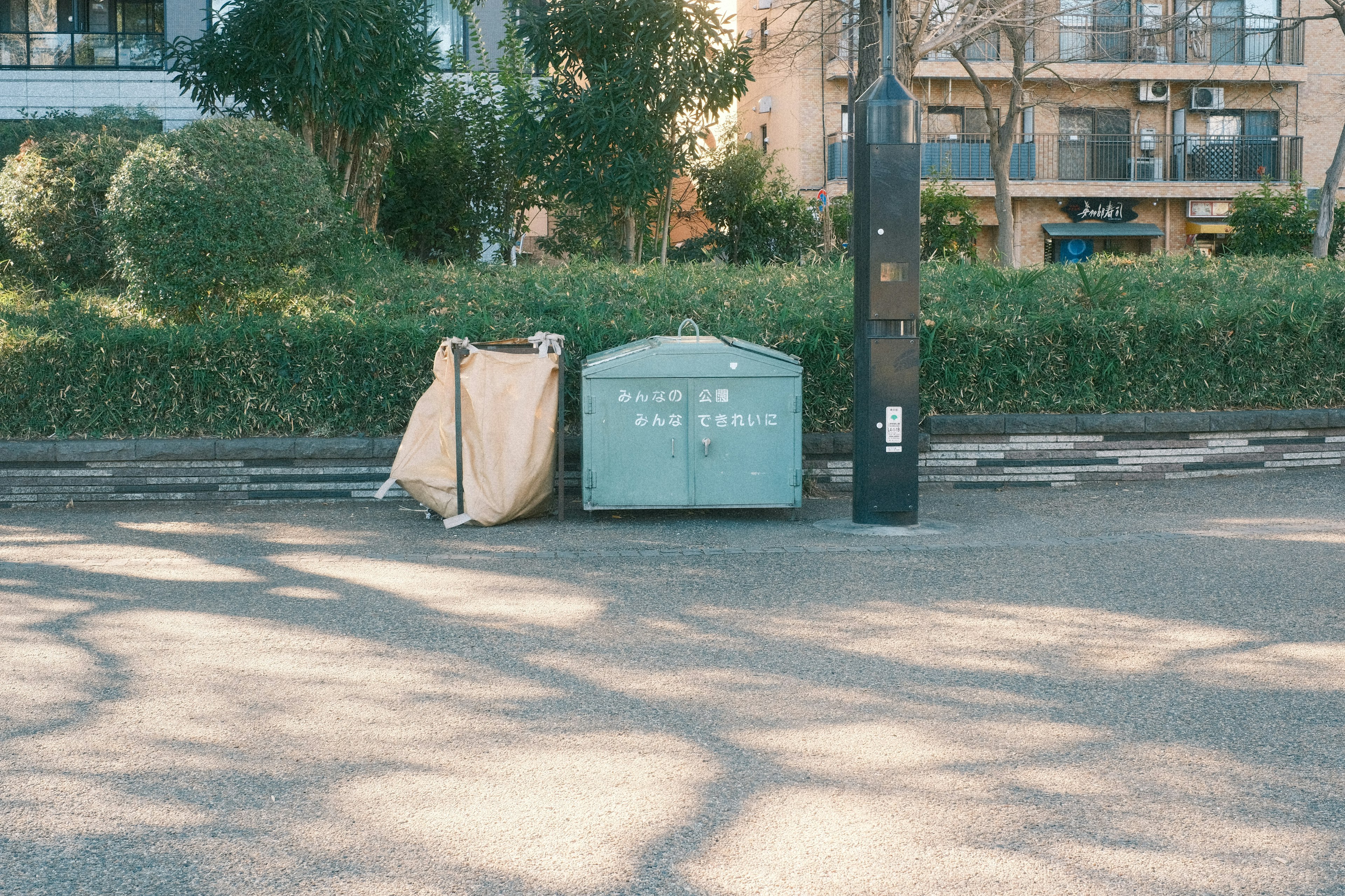 Green trash bin and brown tarp in a park corner