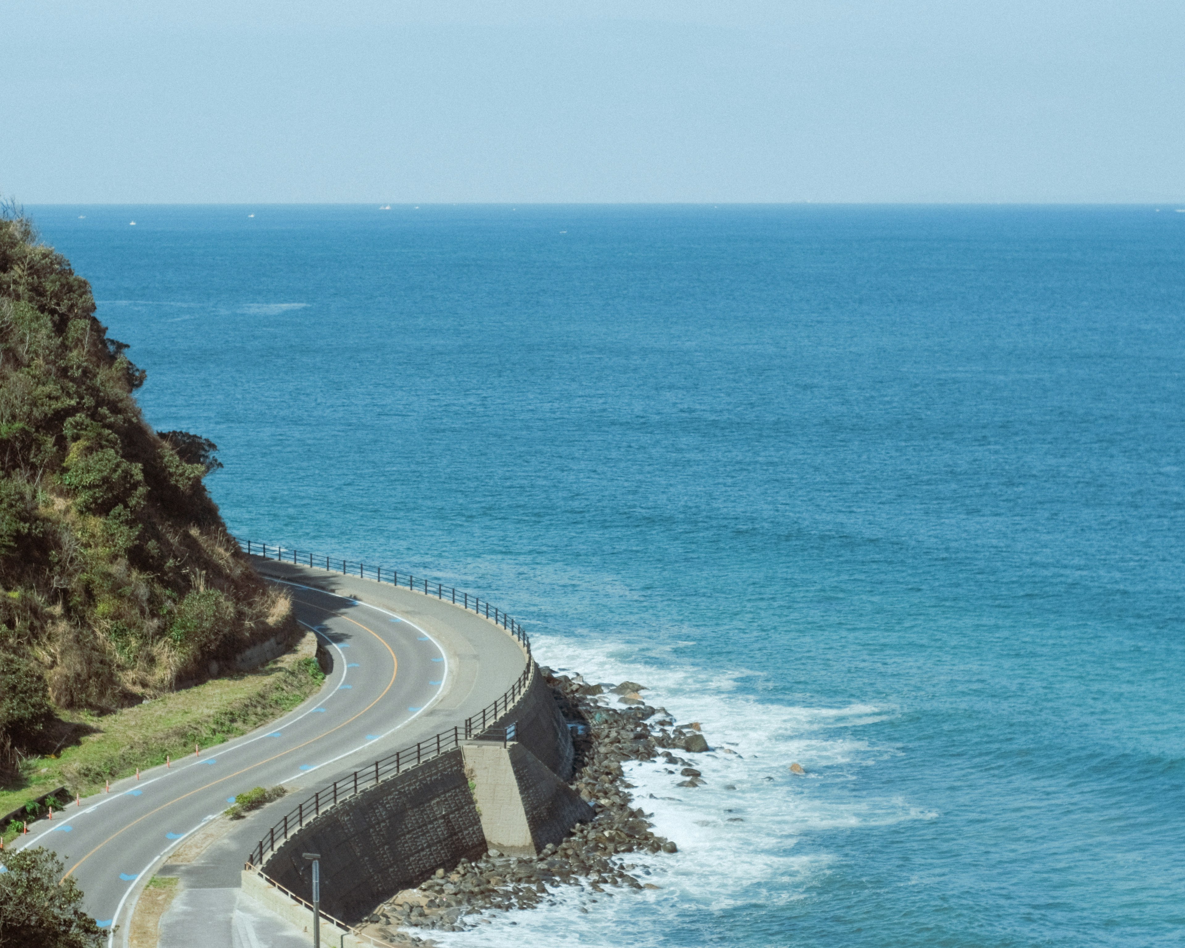 Scenic view of a winding road along a blue ocean