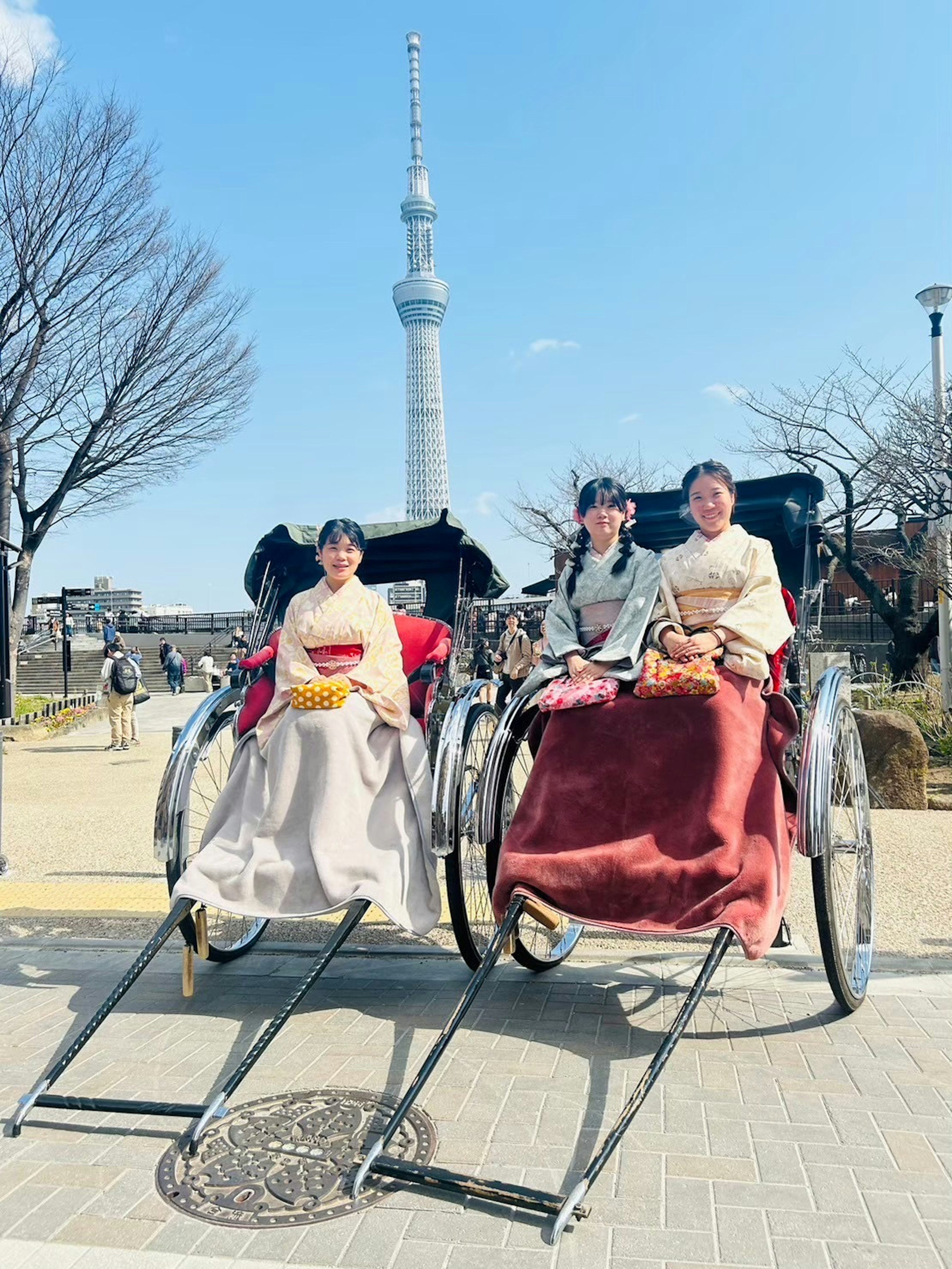 東京スカイツリーの前で人力車に乗った二人の女性が和服を着ている