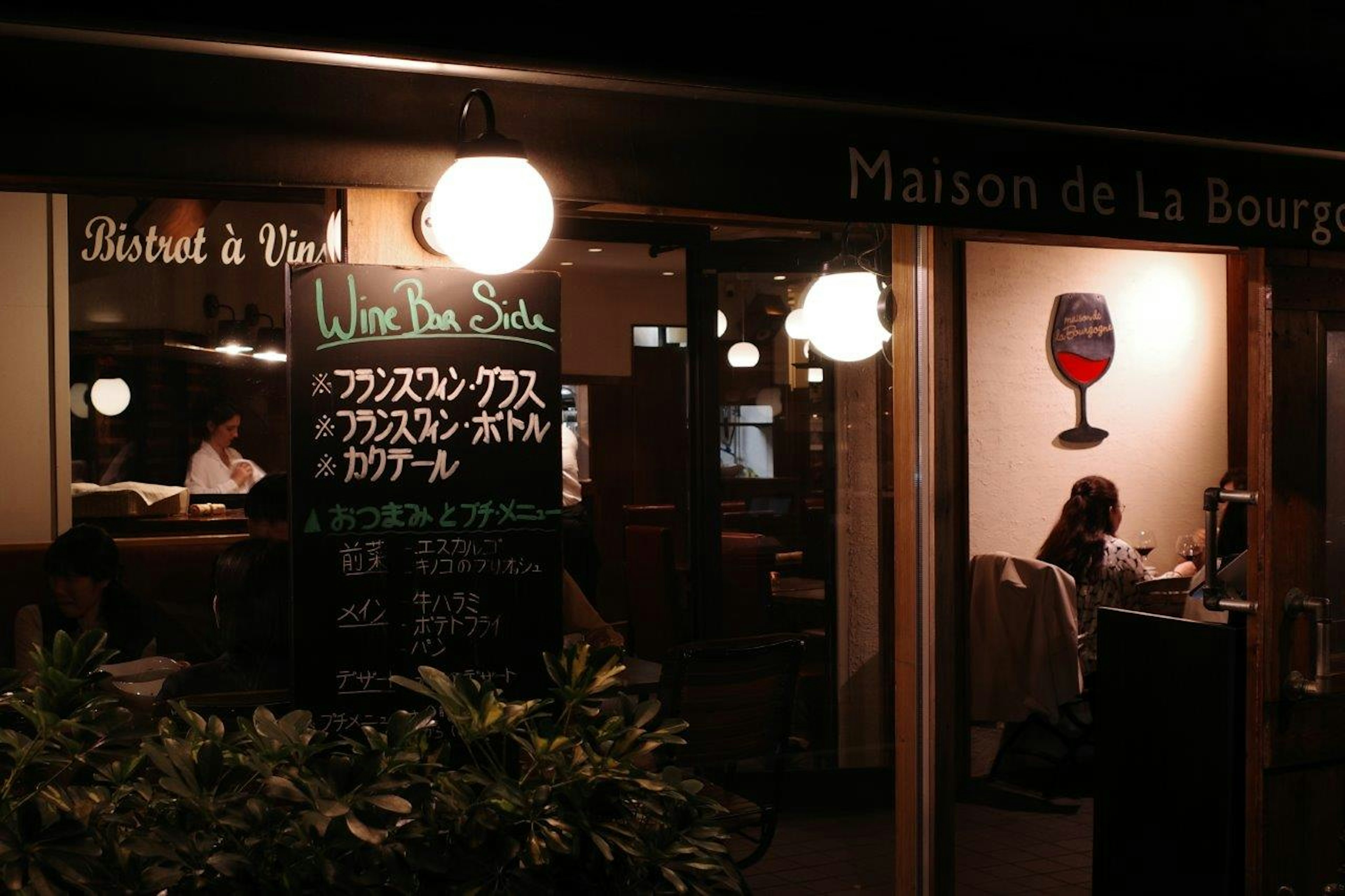 ภายนอกของร้าน Maison de La Bourgogne ในตอนกลางคืนพร้อมป้ายเมนูและแสงไฟอบอุ่น