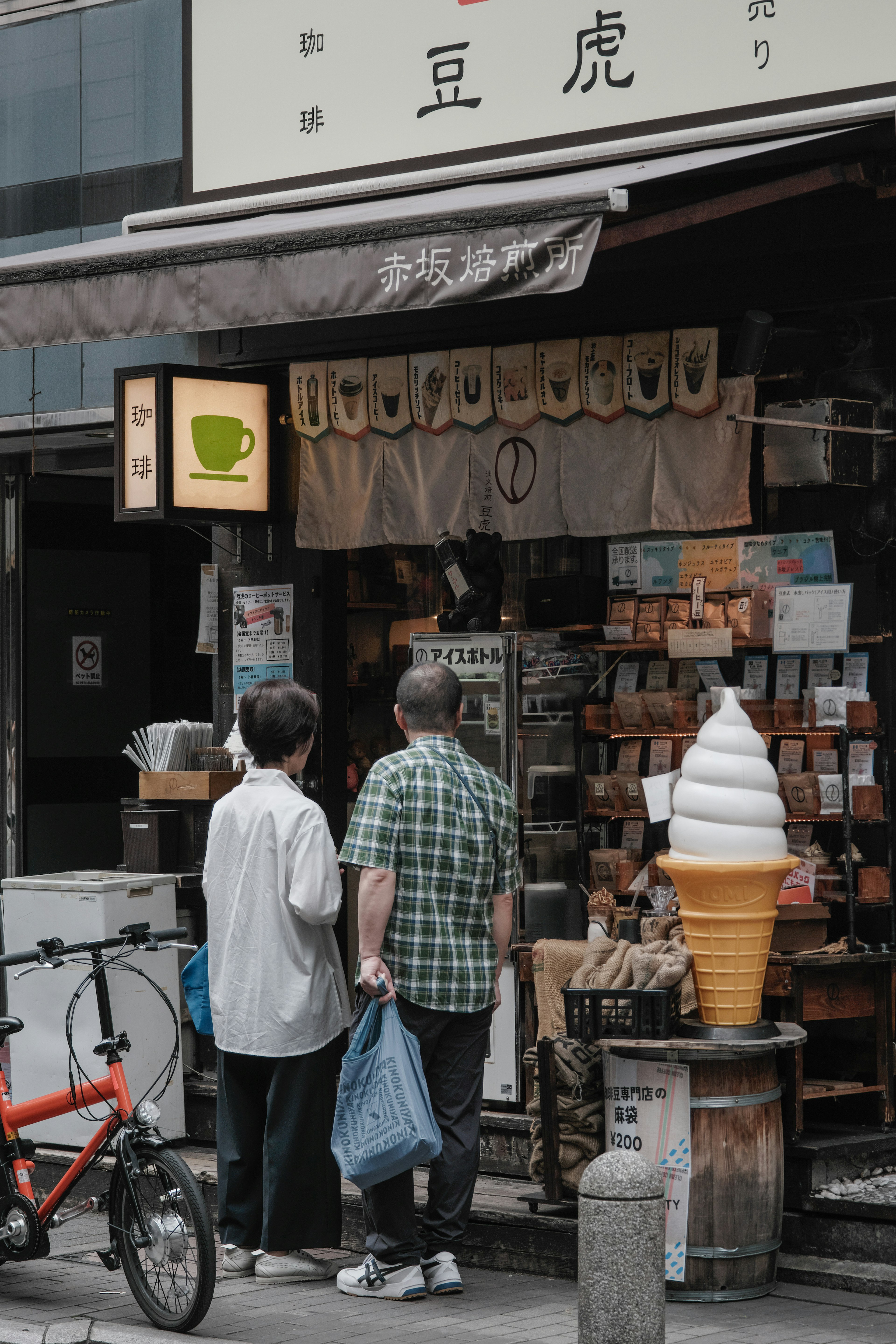 Dos hombres frente a una cafetería con una exhibición de conos de helado