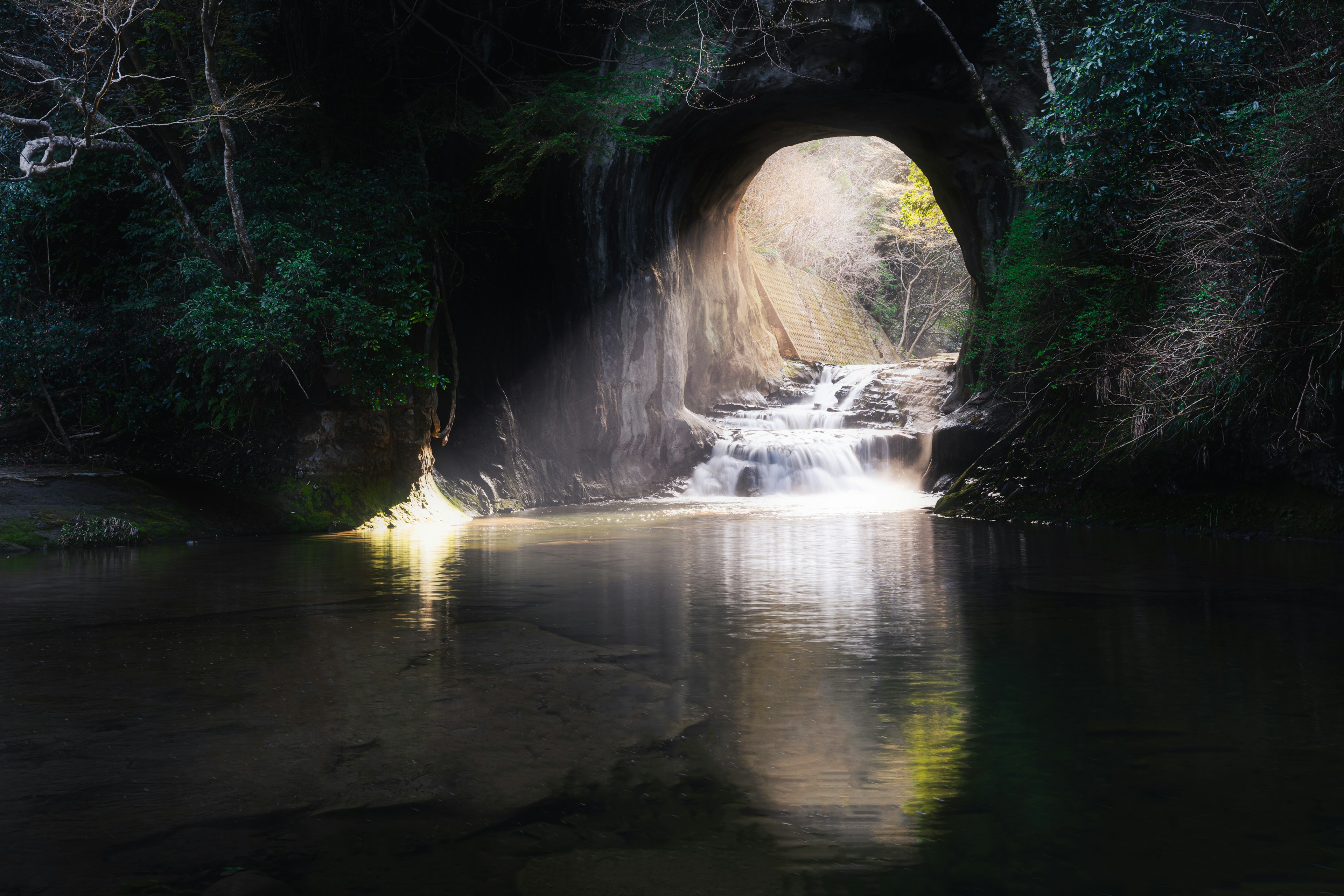 Vista escénica de una cueva con una cascada y luz que entra