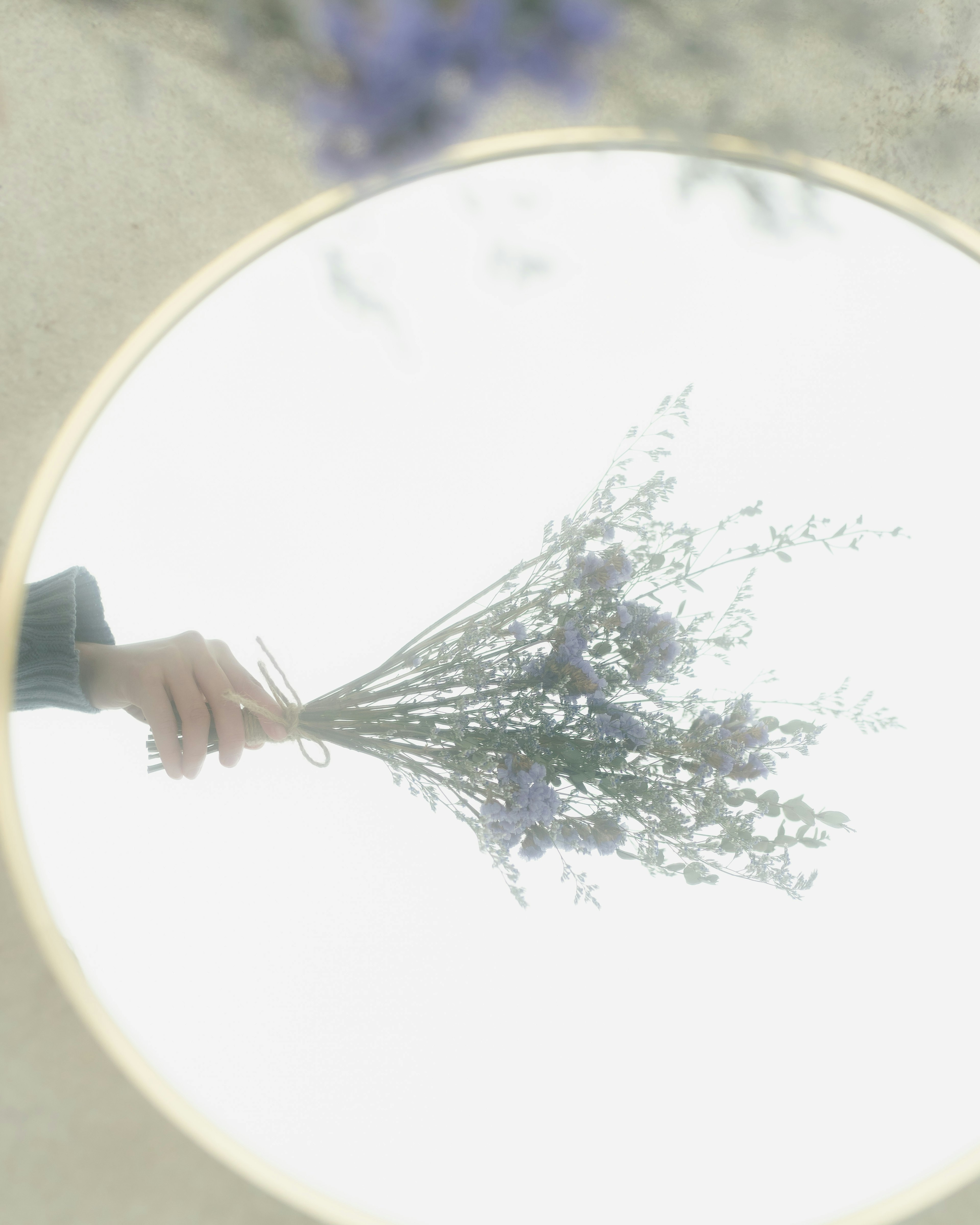 A bouquet of flowers reflected in a round mirror