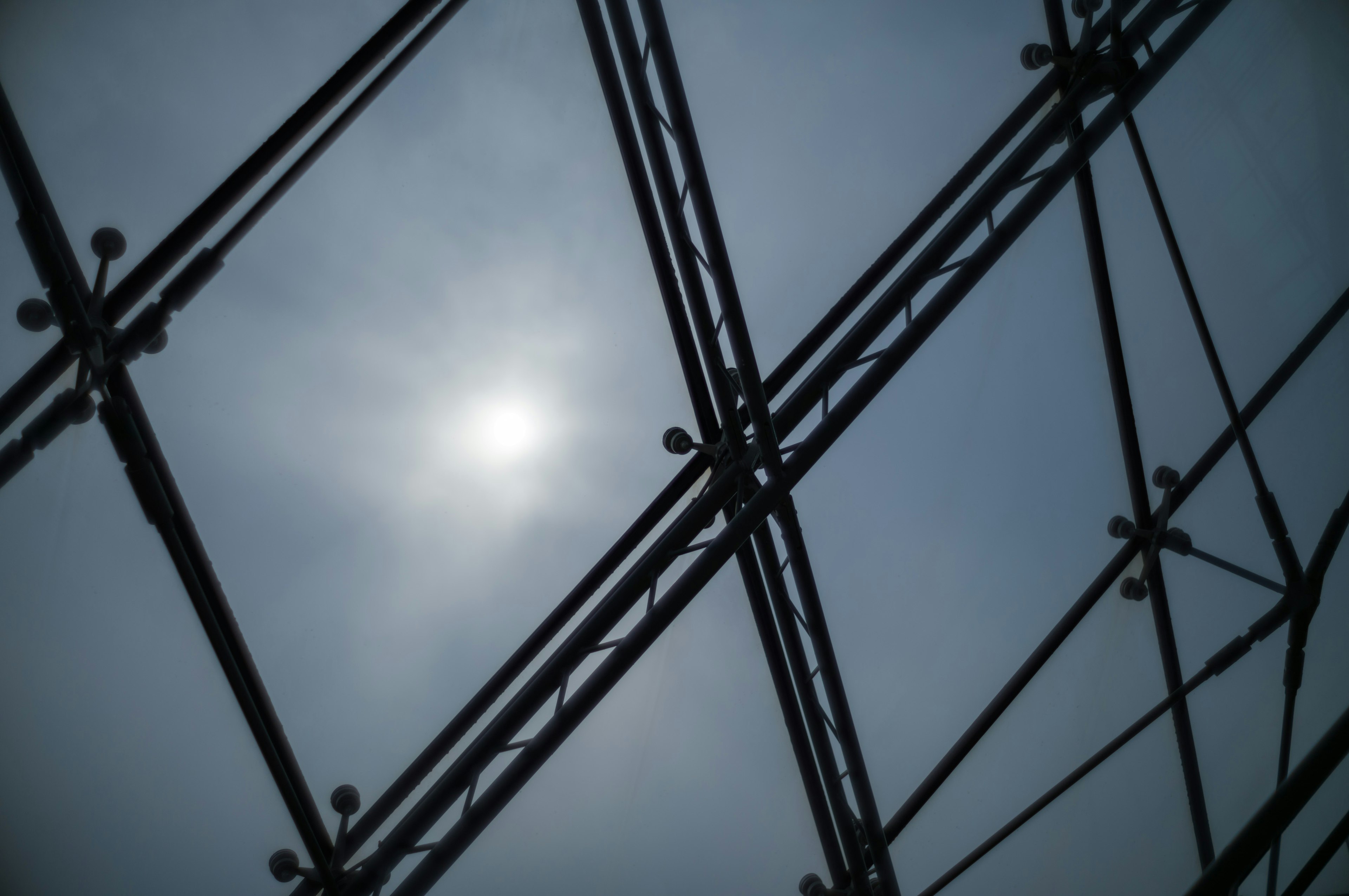 Steel framework with sun partially obscured by clouds