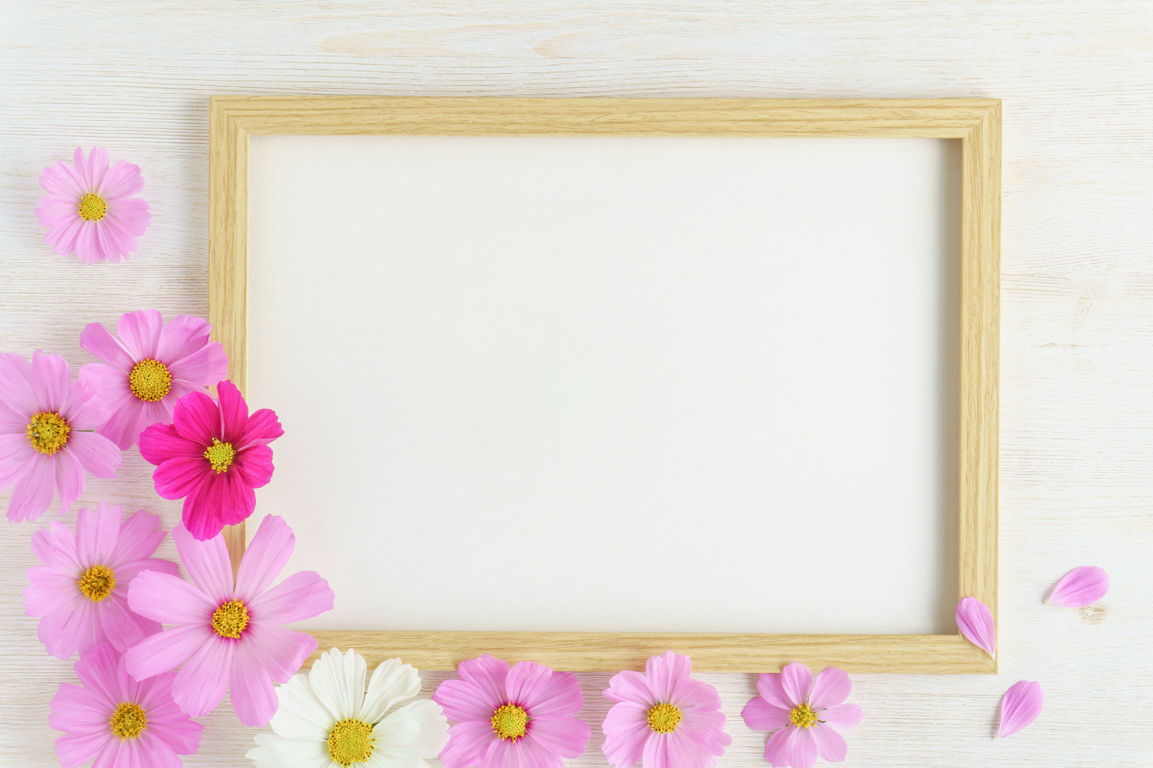 Cadre en bois avec un espace blanc entouré de fleurs roses et blanches