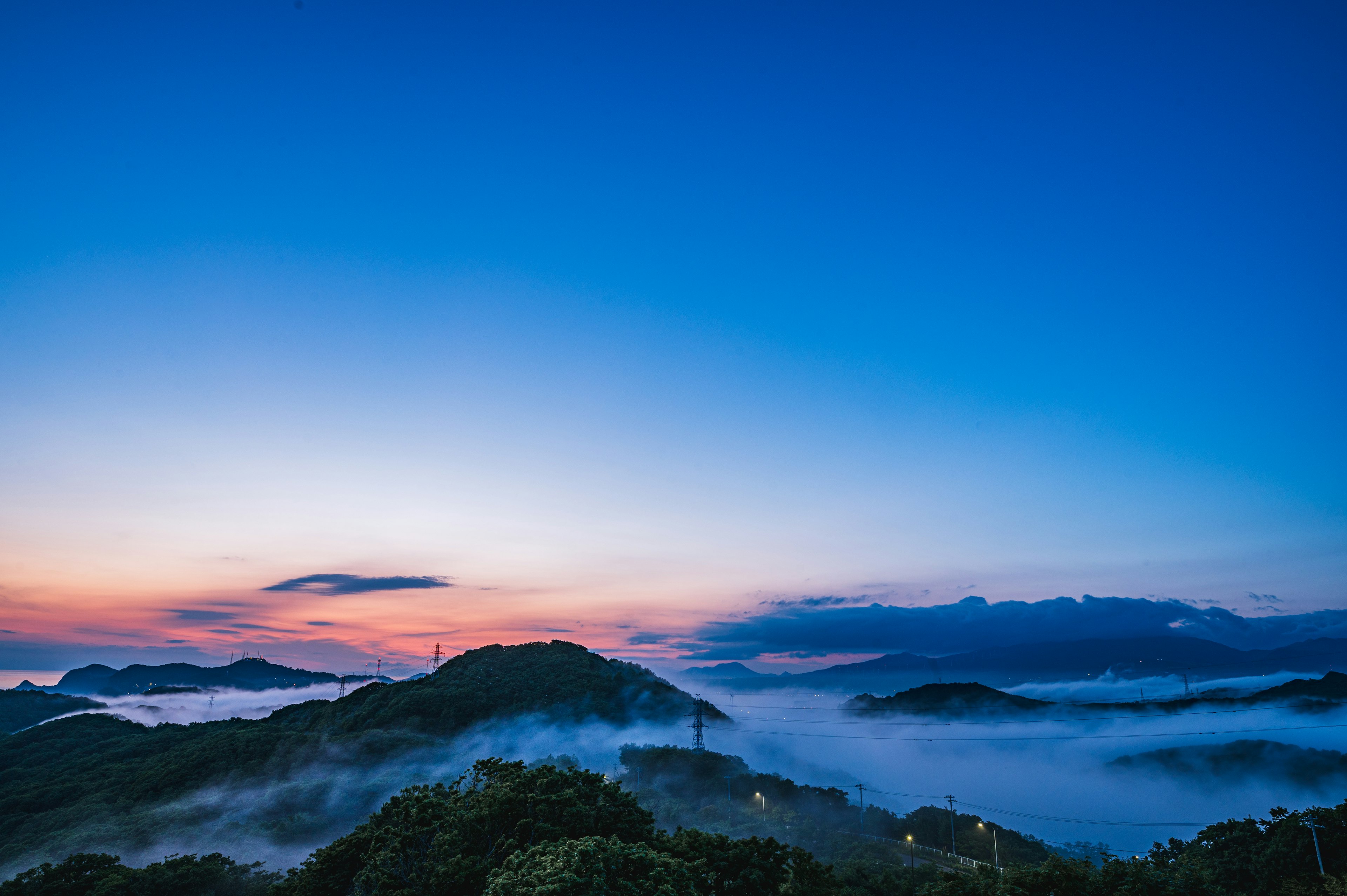 藍天下籠罩在霧中的山丘風景