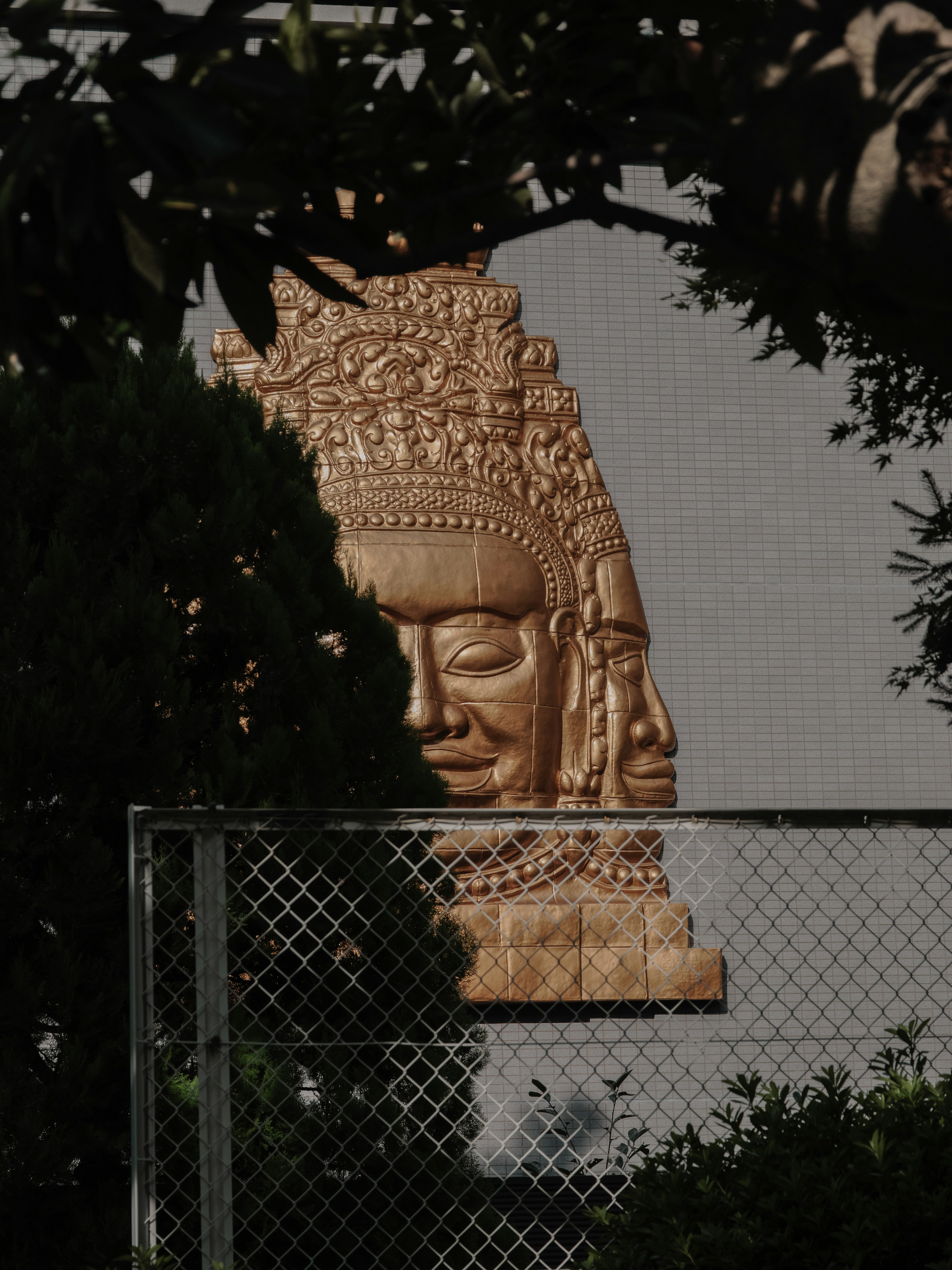 Statue dorée d'un Bouddha partiellement visible derrière une clôture