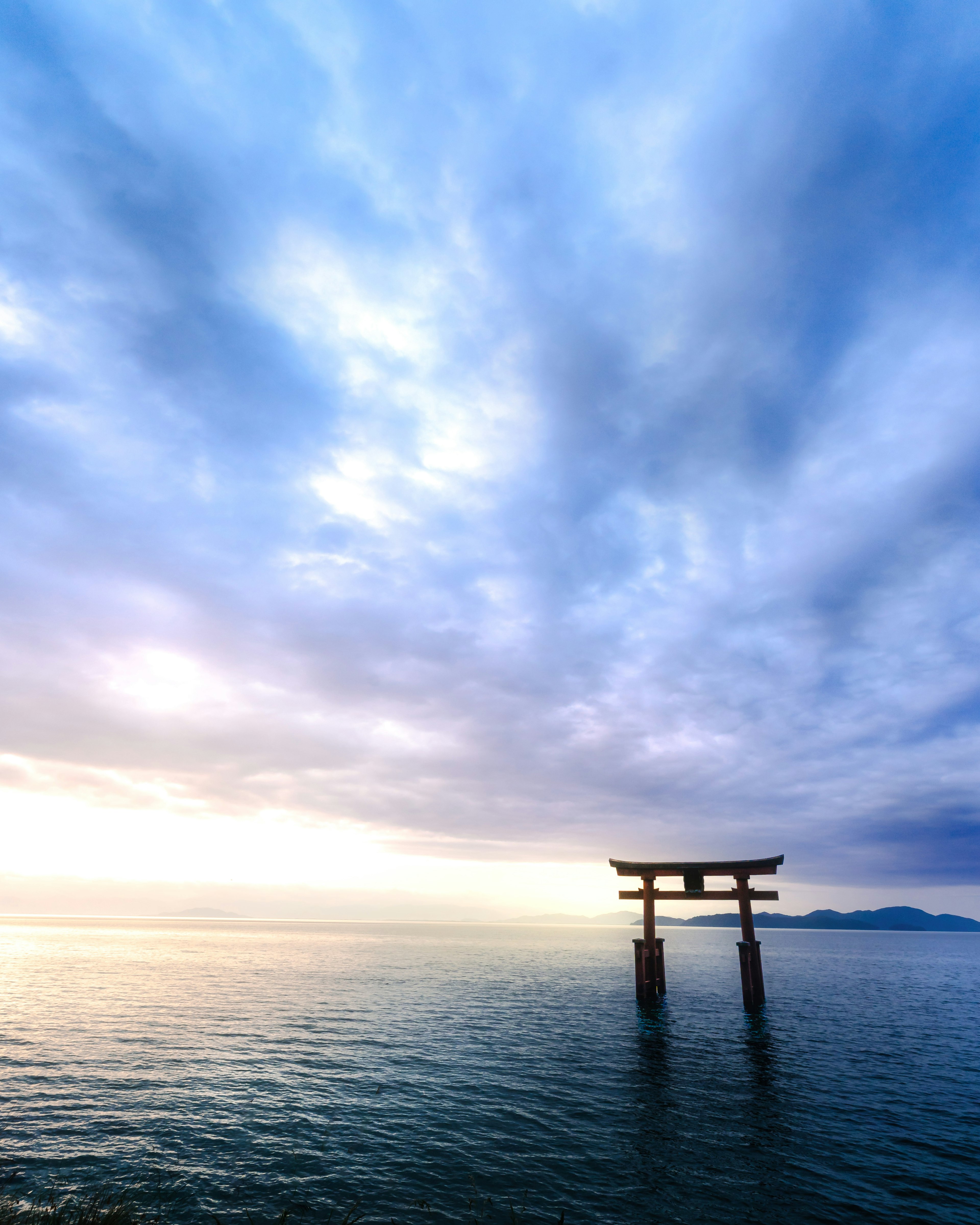 Gerbang torii berdiri di laut dengan langit yang tenang