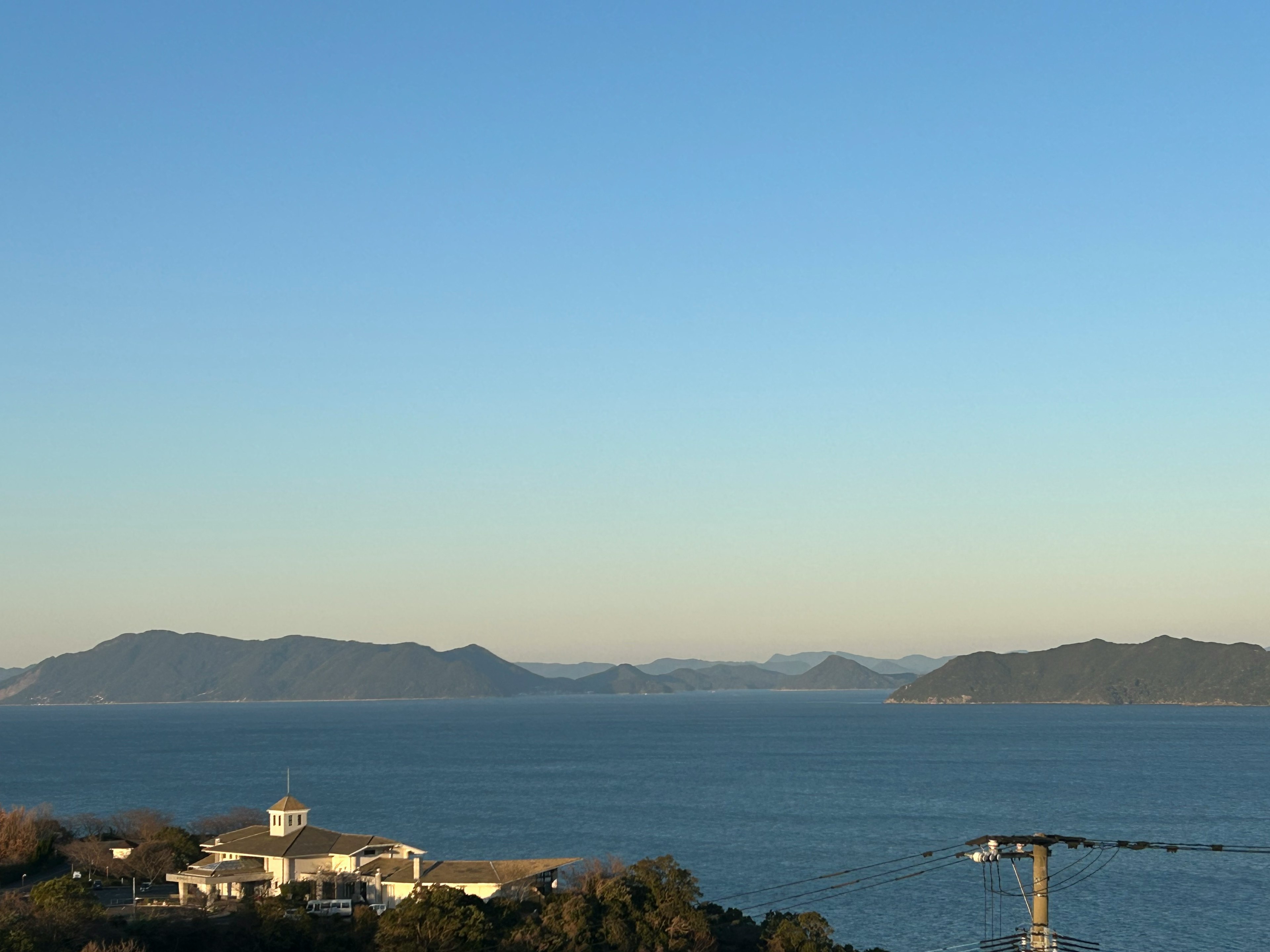 Scenic view with blue sky and ocean featuring nearby building and islands