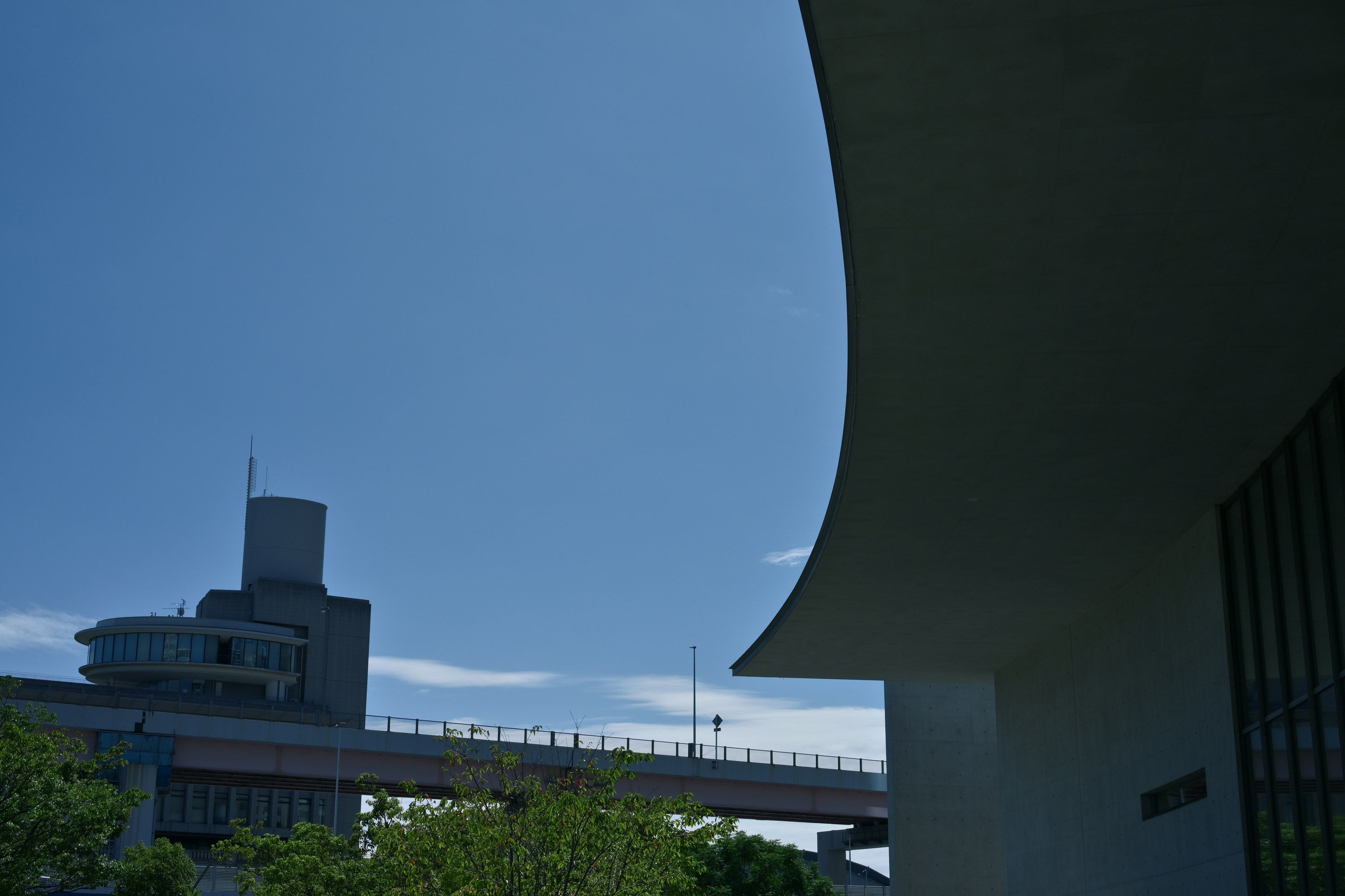 青空と曲線的な建物の一部が映る風景