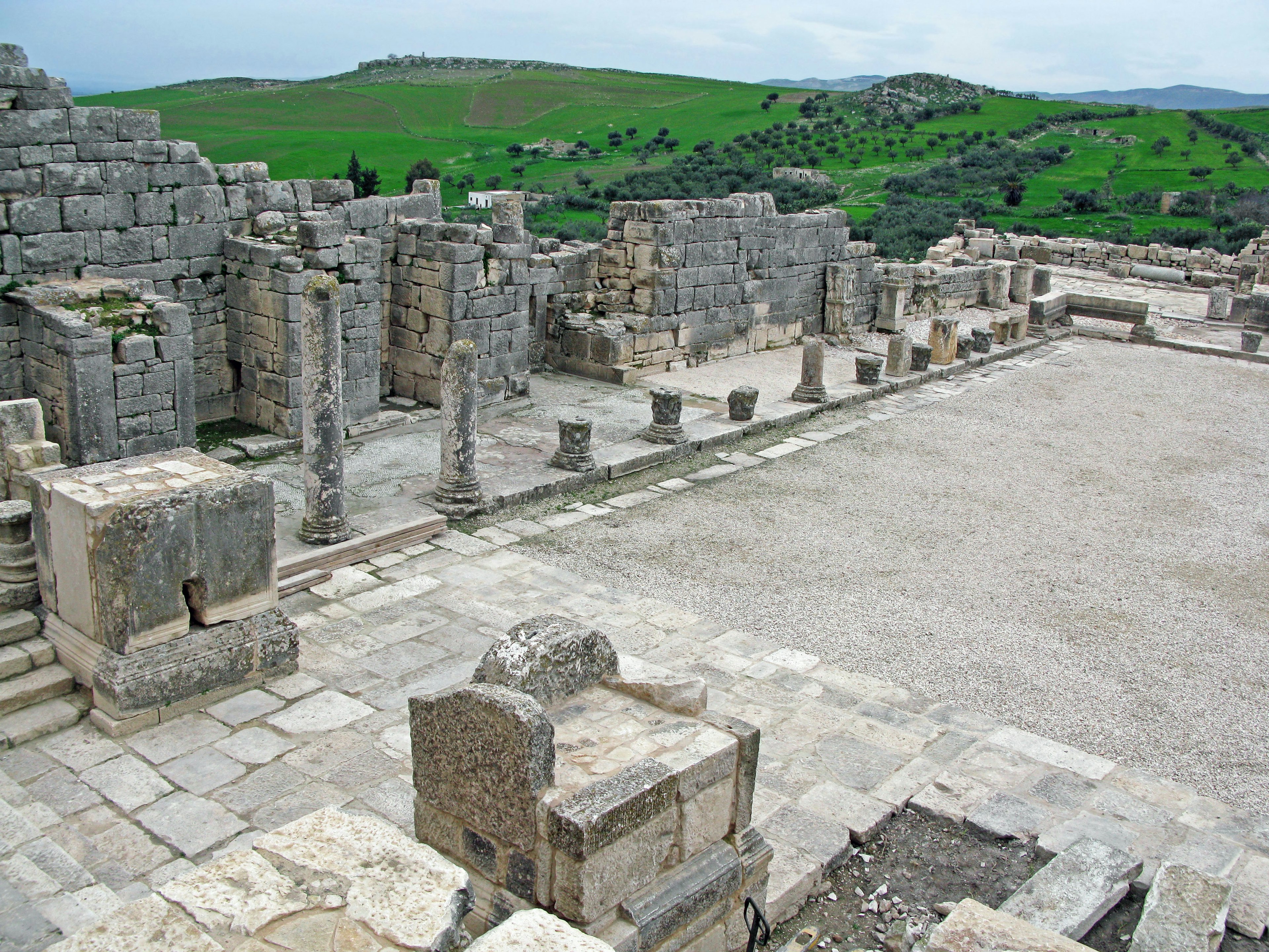 Ancient ruins with stone structures and green hills in the background