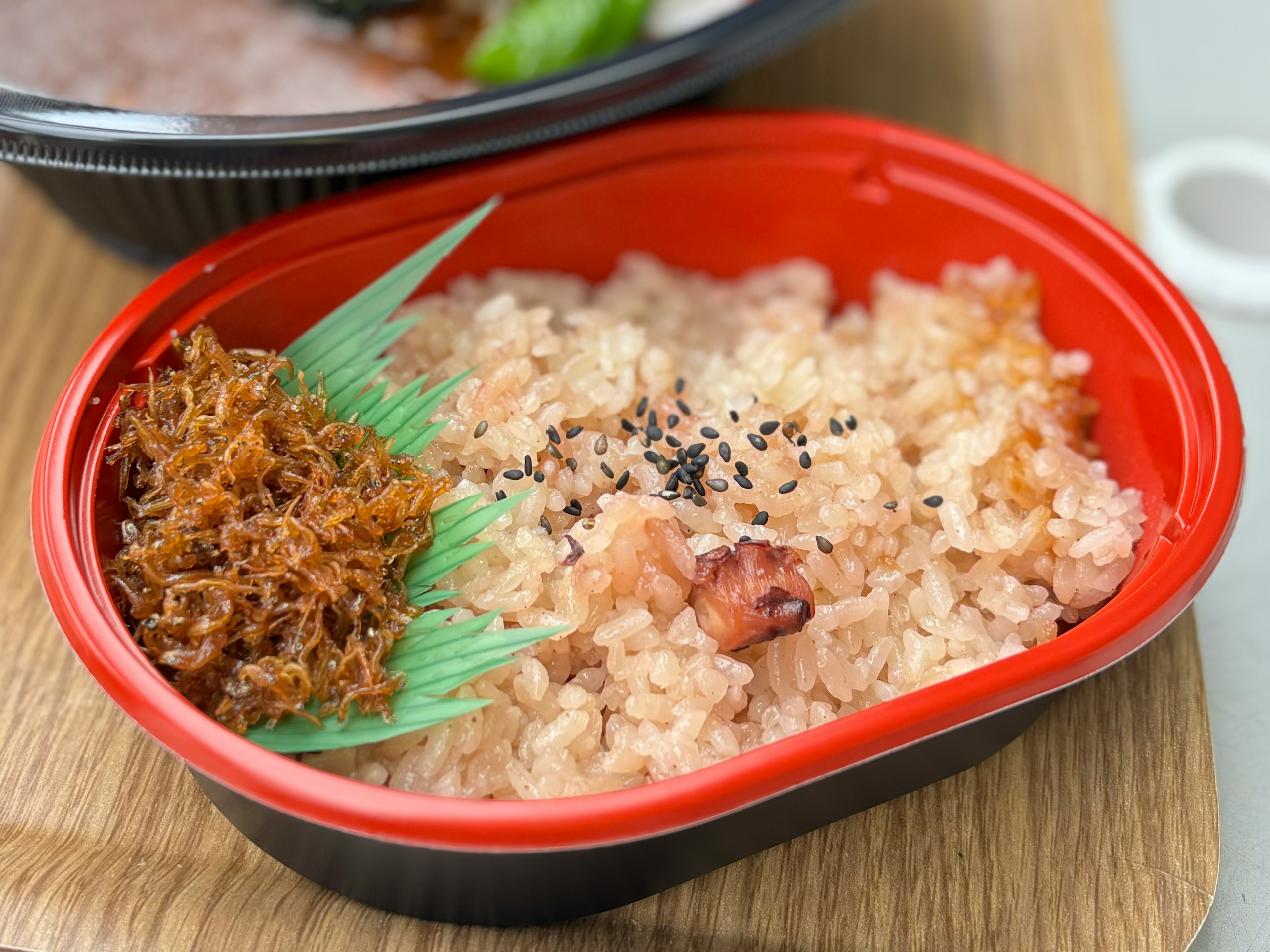 赤い容器に盛られた香ばしいご飯と海苔のトッピング