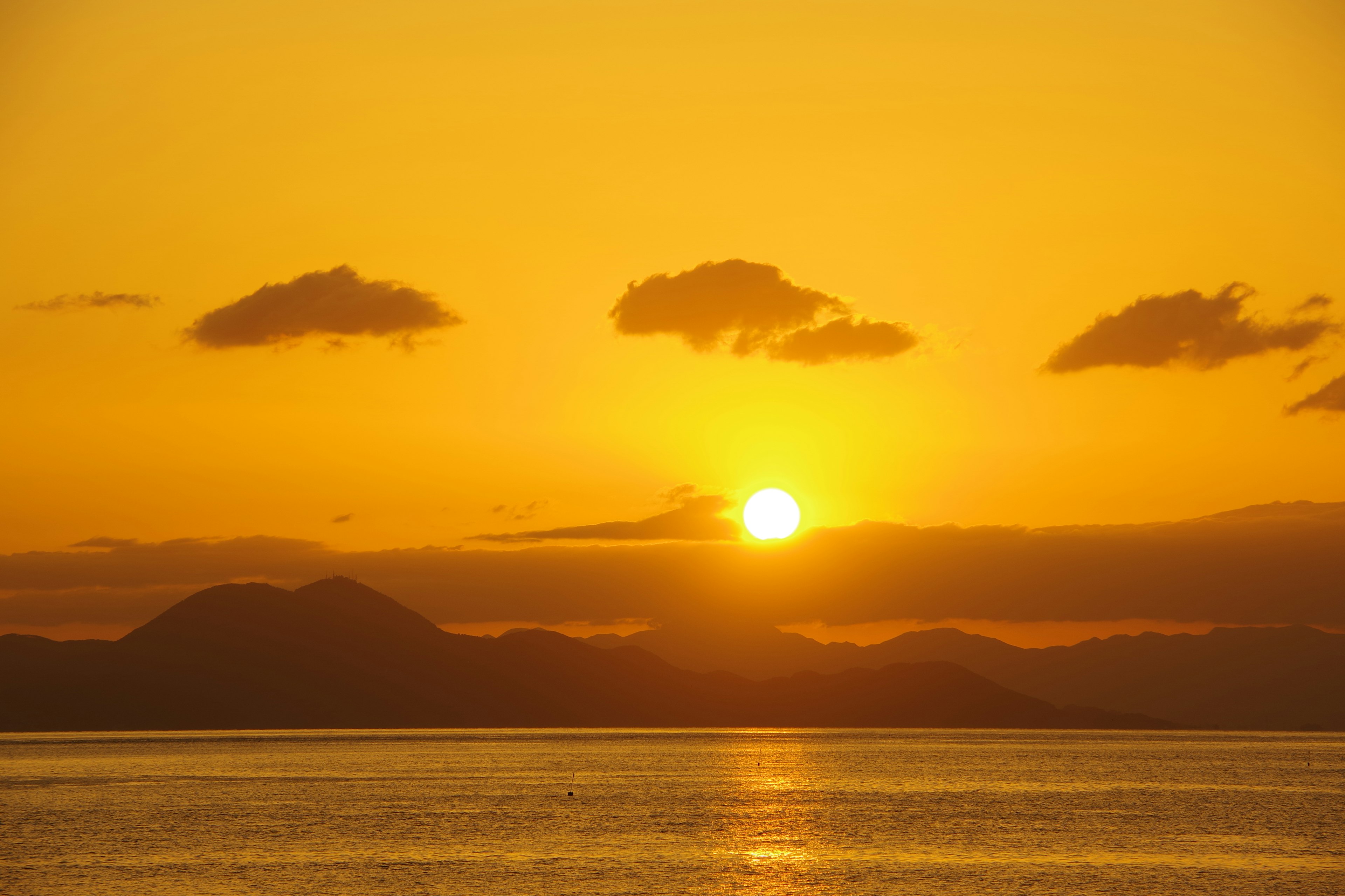 Wunderschöner Sonnenuntergang über dem Ozean mit silhouettierten Bergen