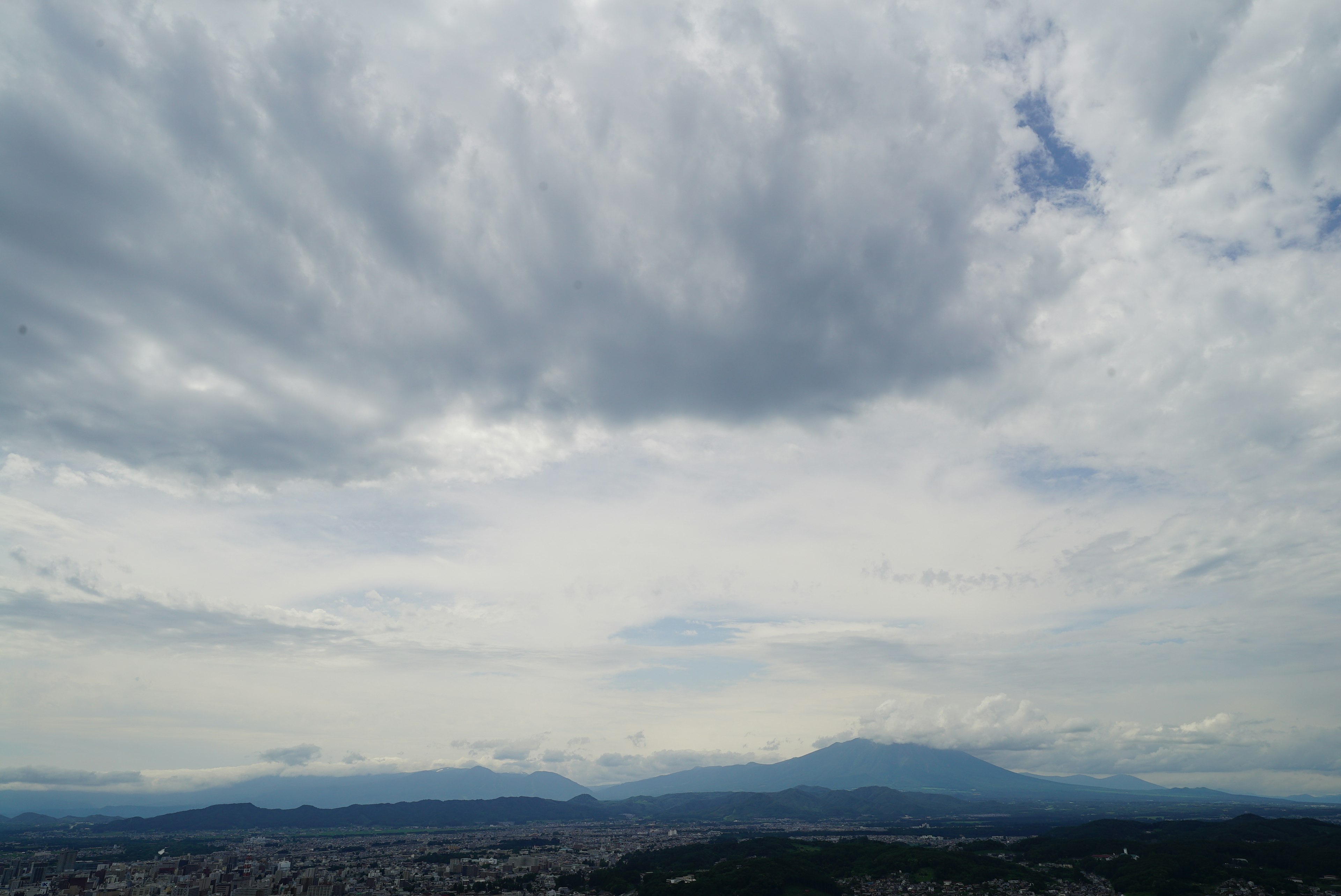 Cloudy sky with distant mountains and cityscape