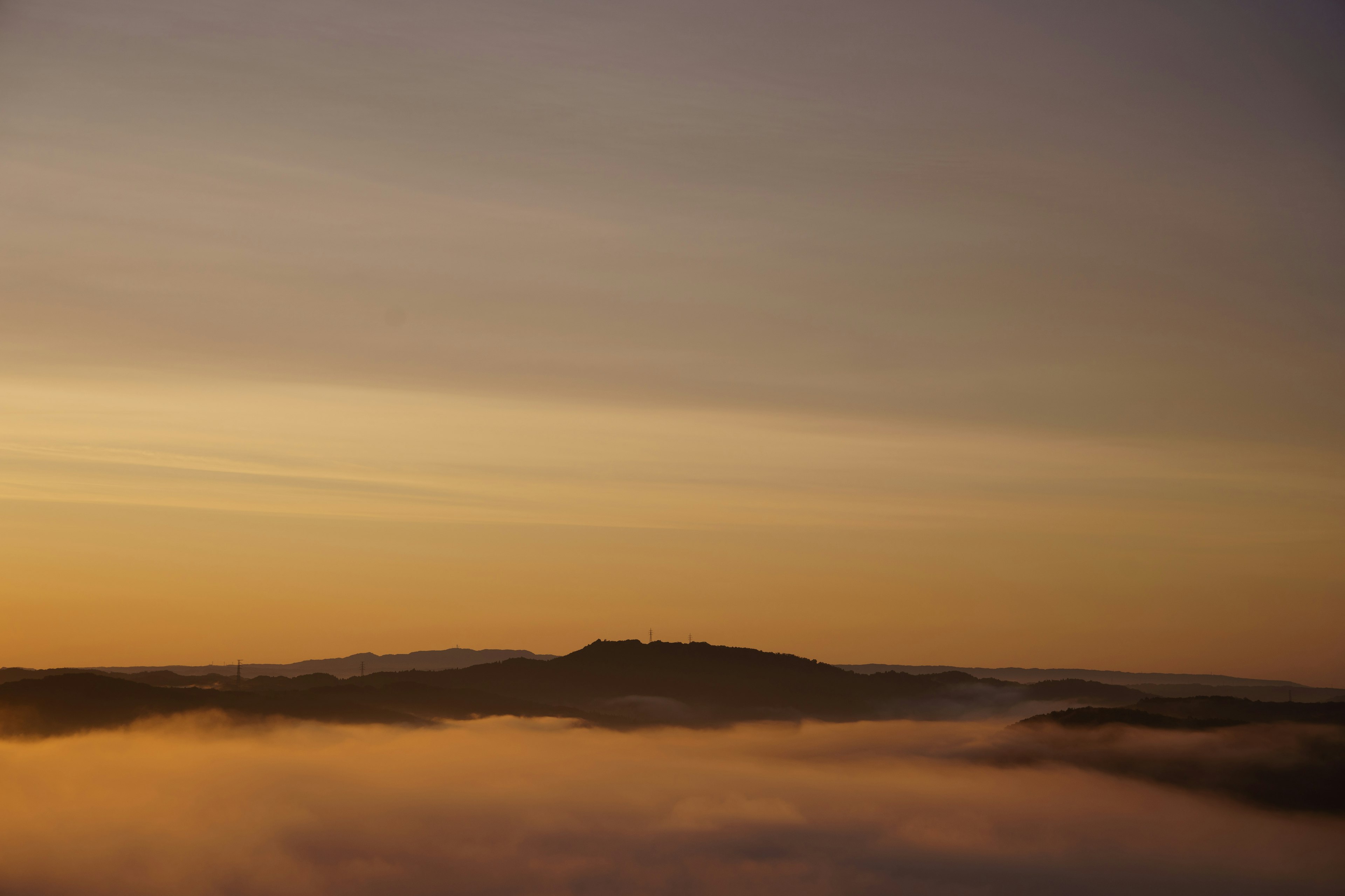 Berg in Nebel gehüllt mit einem orangefarbenen Himmel