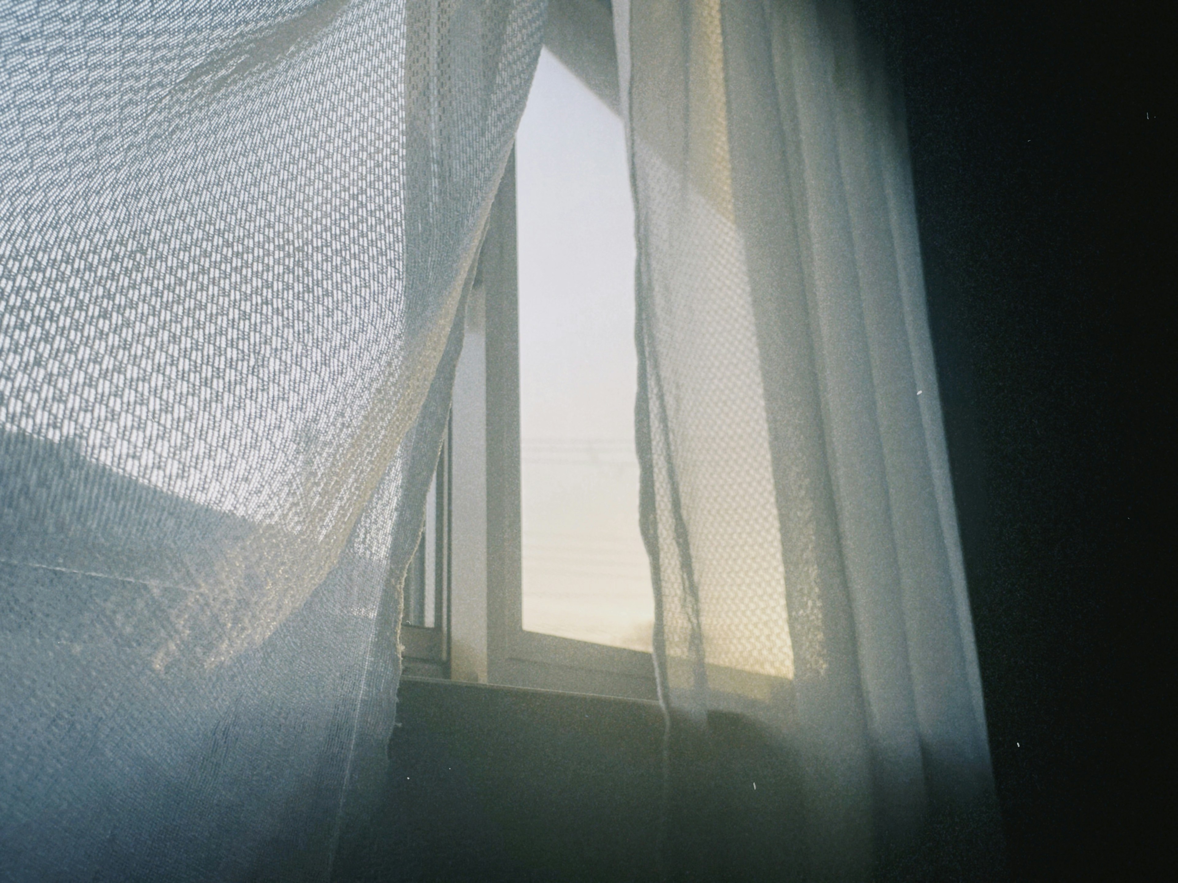 Soft light filtering through a sheer curtain by the window