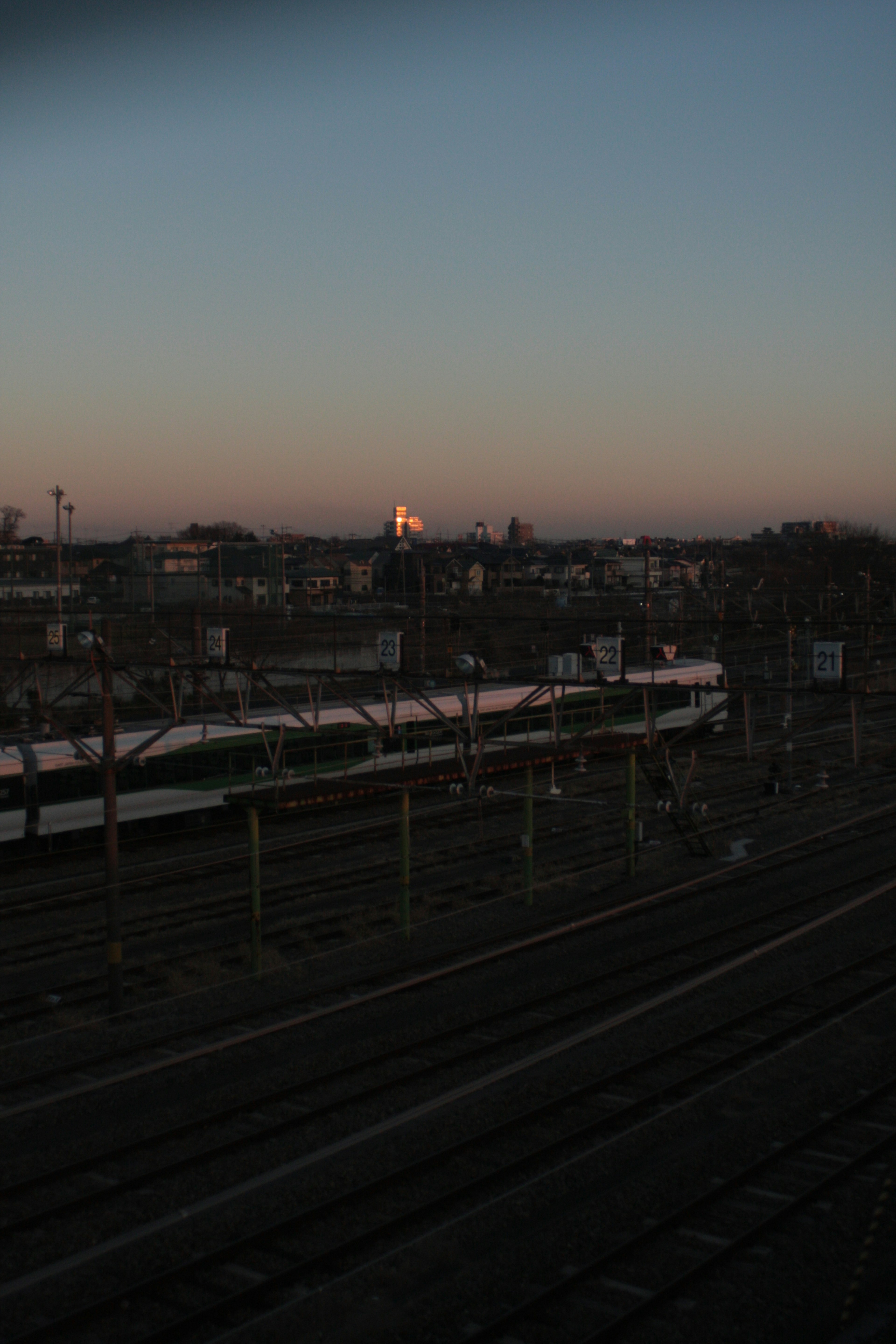 Vista al atardecer de una estación de tren con vías y edificios