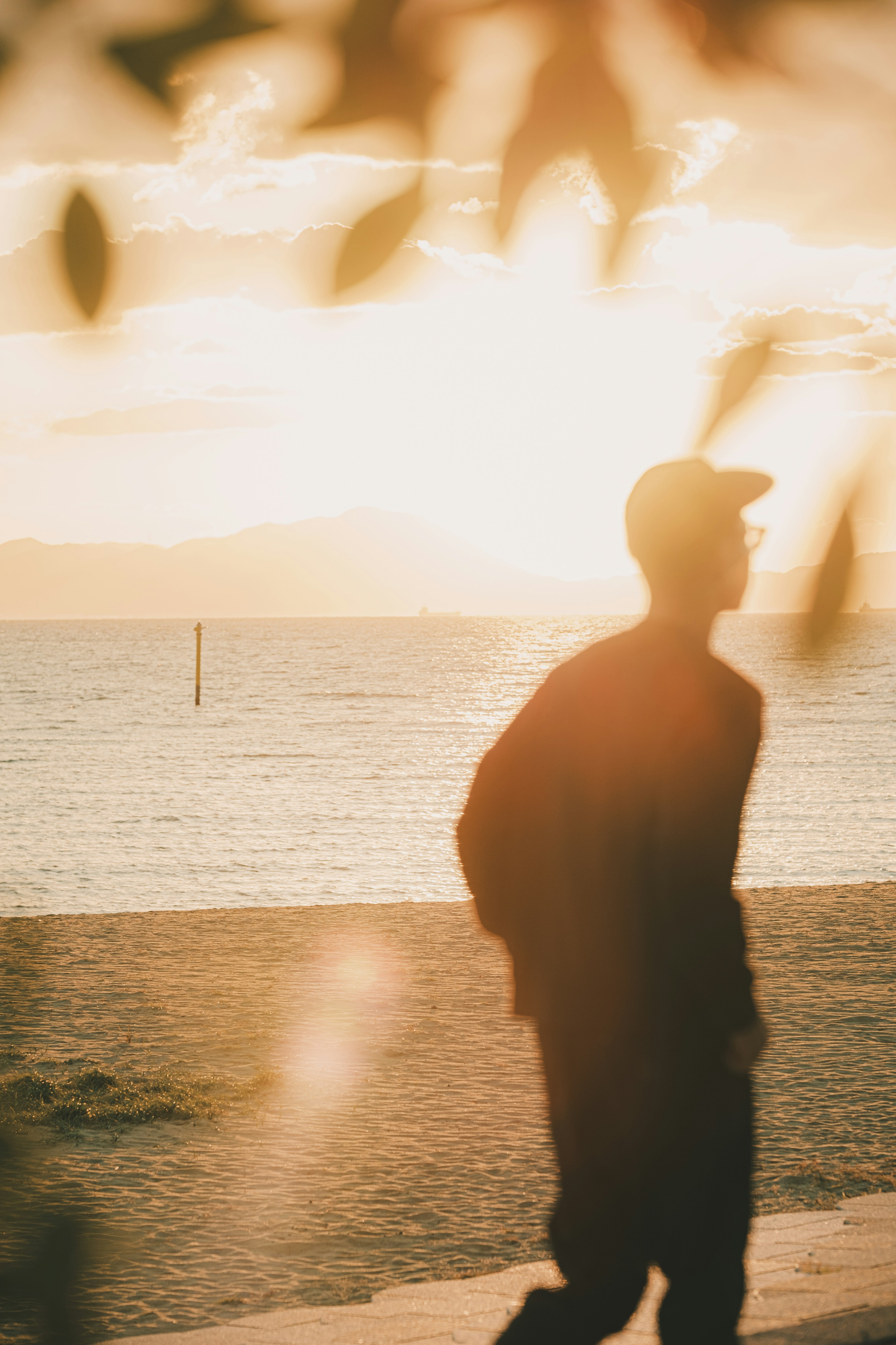 Silhouette eines Mannes, der am Strand mit Sonnenuntergang im Hintergrund geht