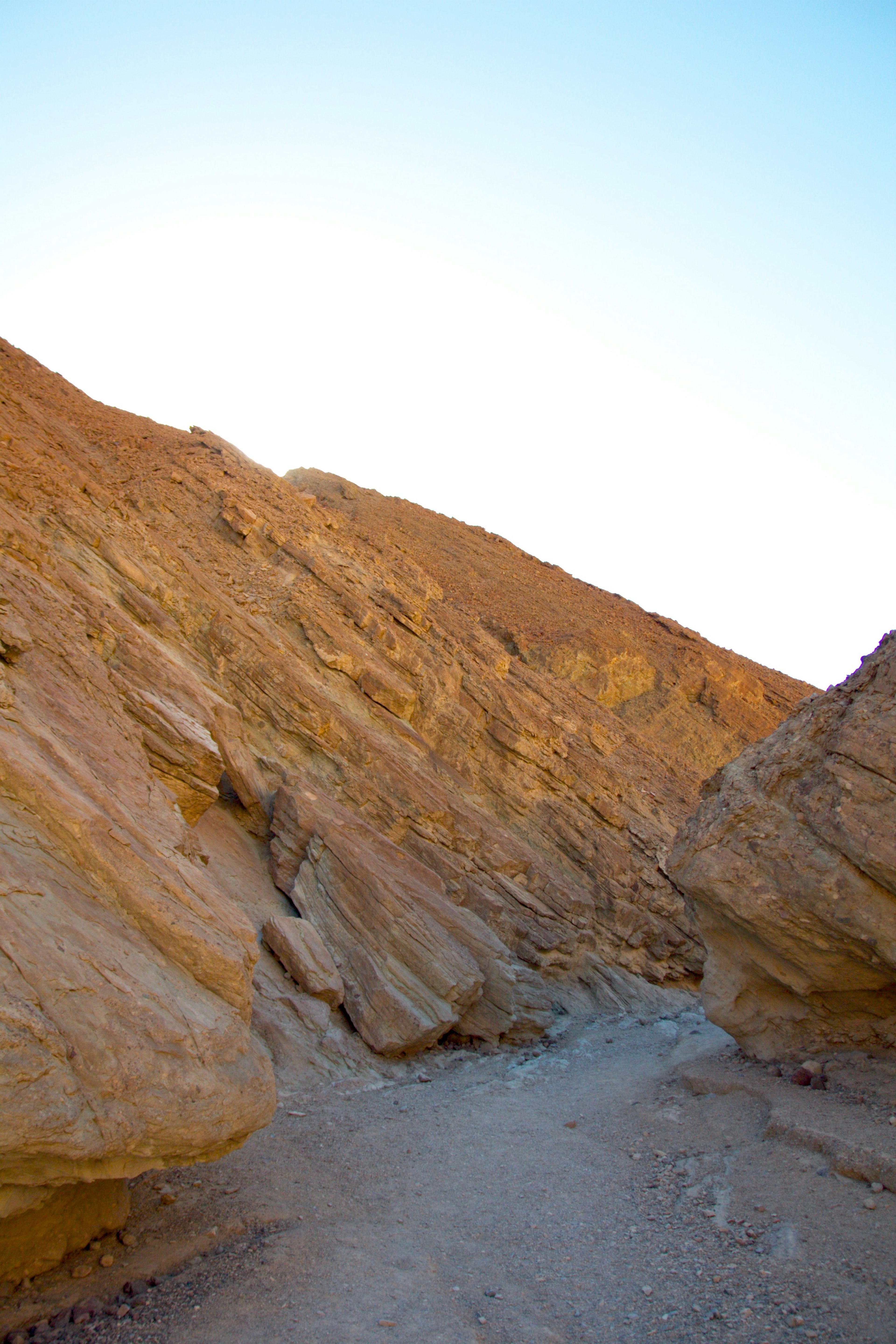 Narrow path between rugged rock formations and clear blue sky