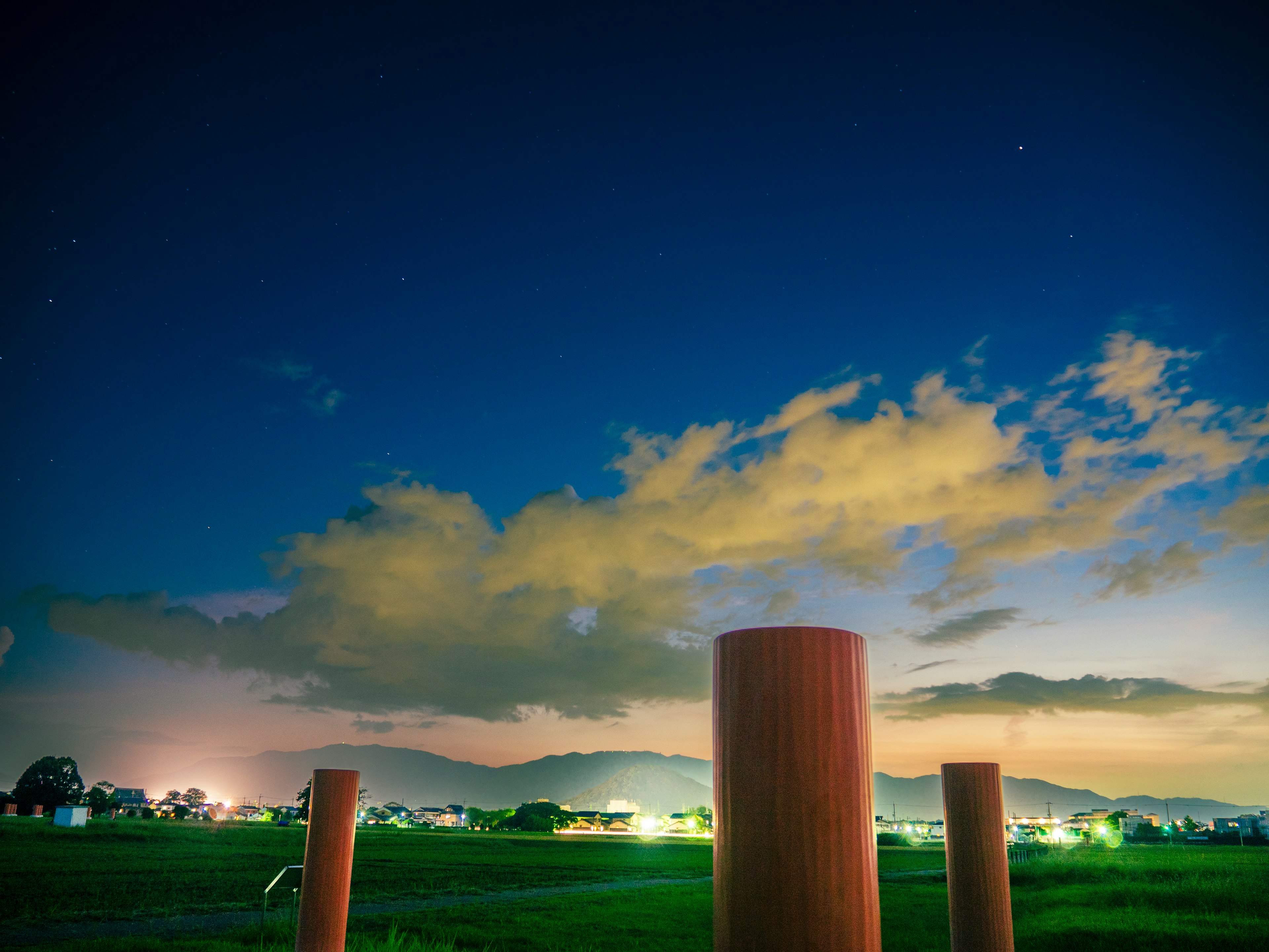 Large cylindrical structures against a twilight sky with clouds and stars