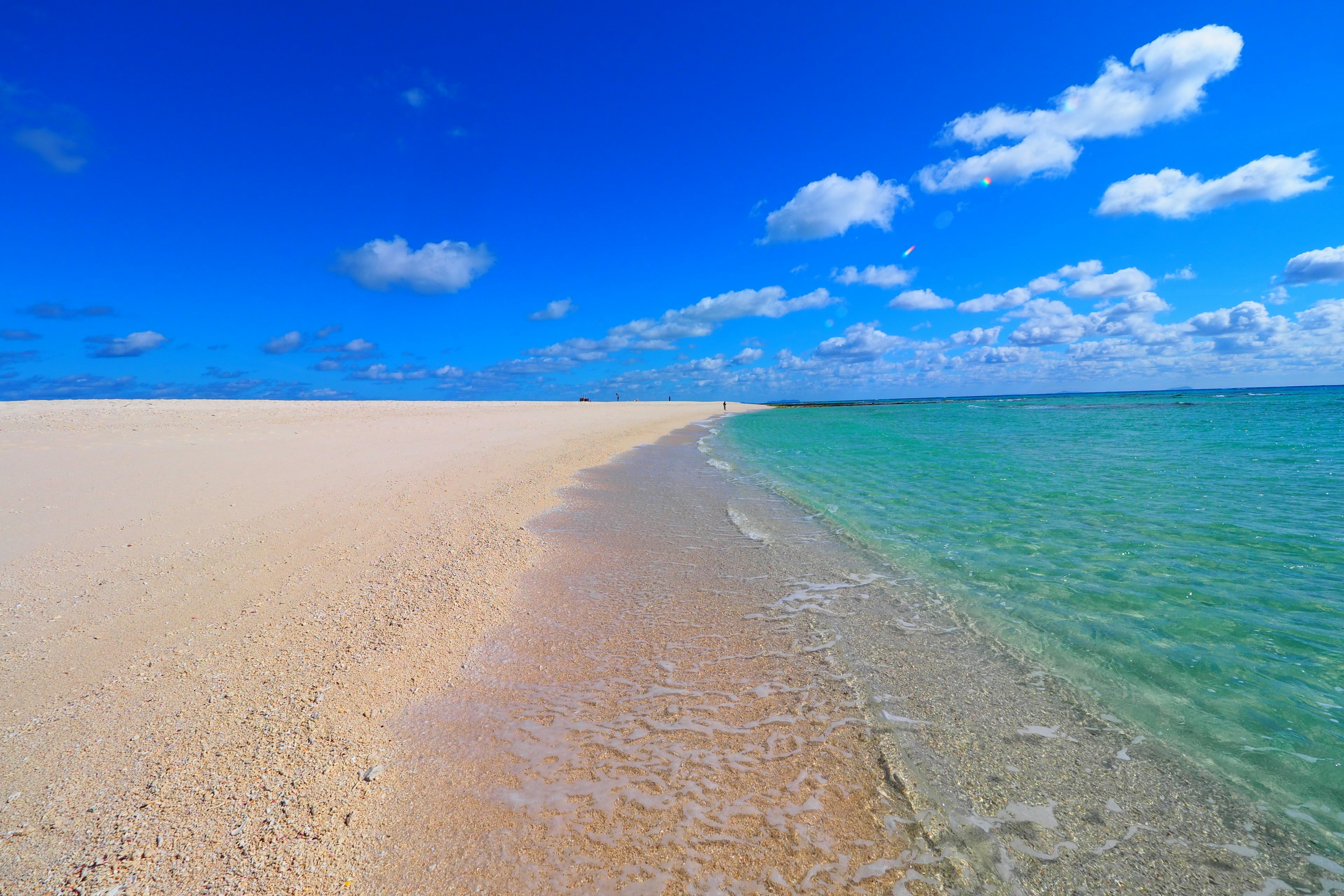 A beach landscape featuring a blue sky and white sandy shore