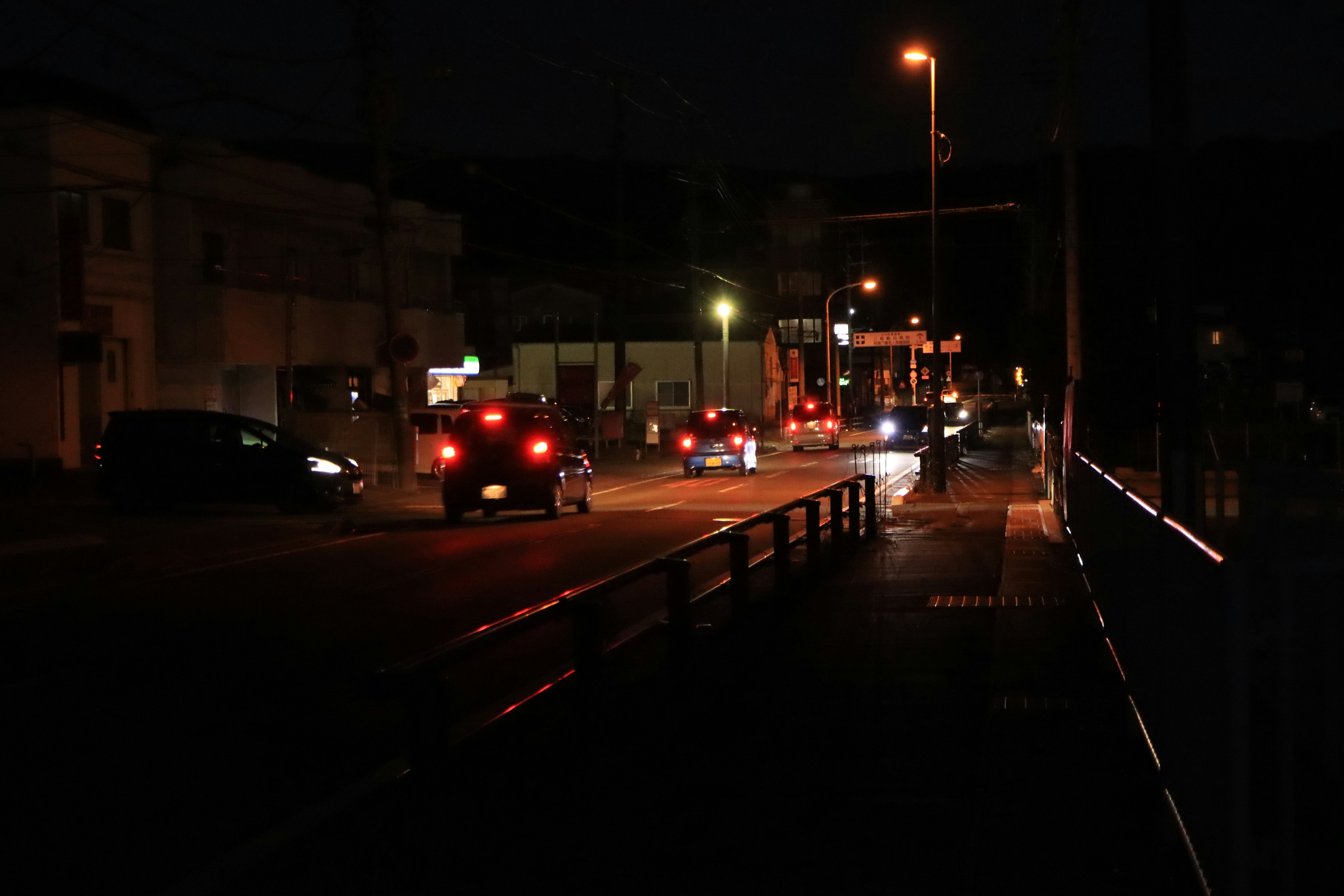 Nighttime street scene with cars driving and streetlights illuminating