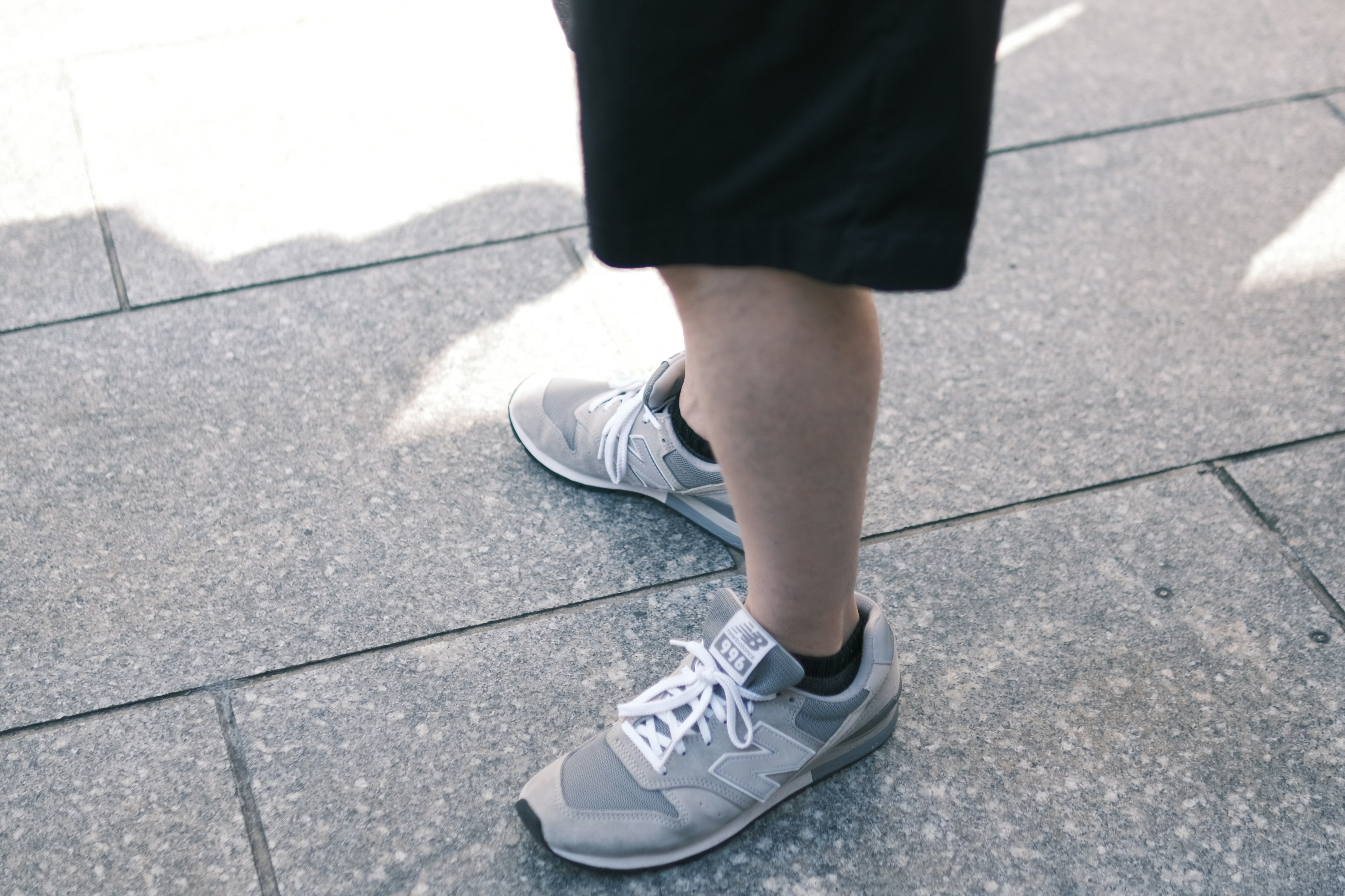 Close-up of feet wearing gray sneakers and black shorts