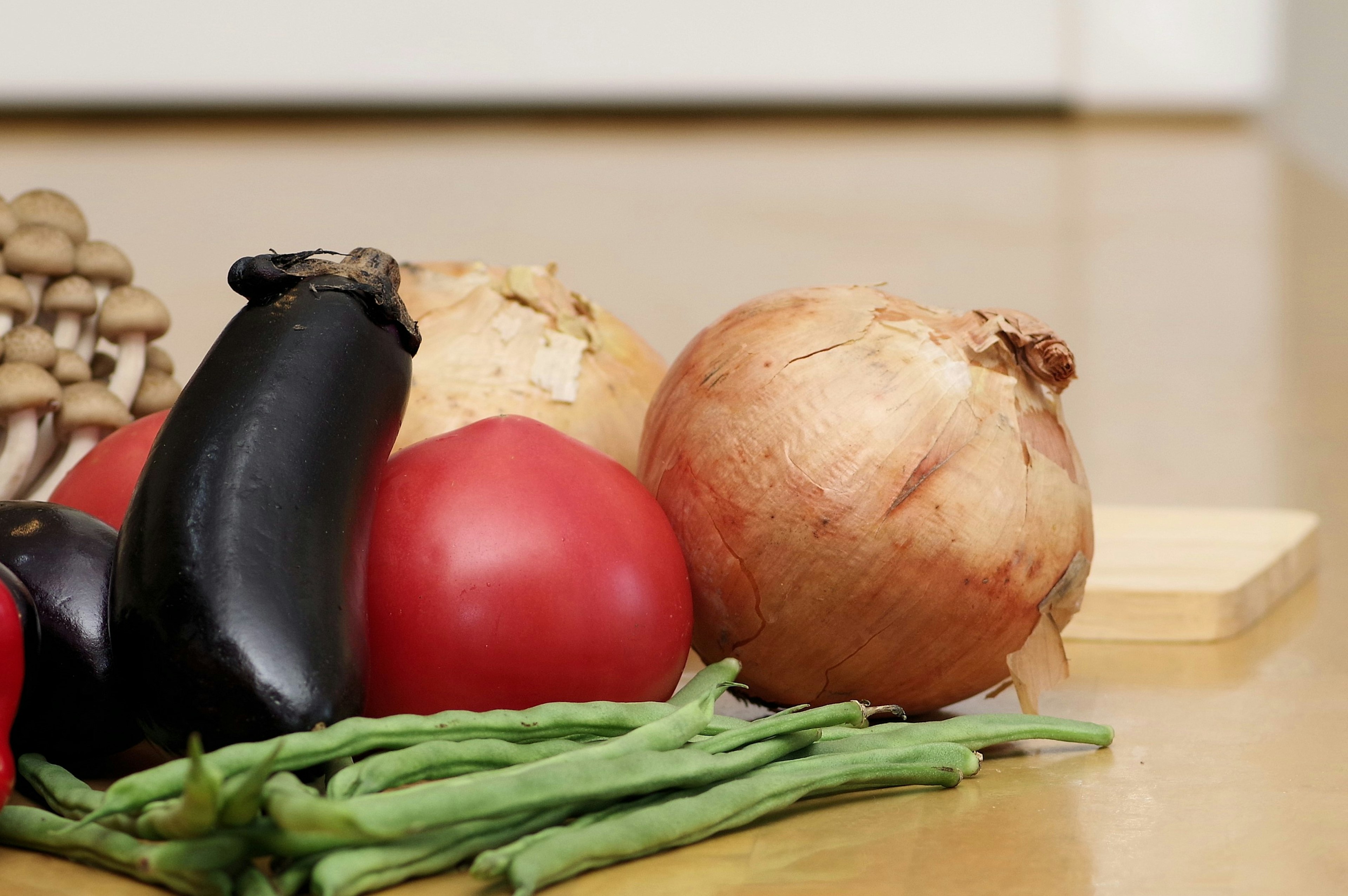 Verdure fresche tra cui melanzane pomodori cipolle e fagiolini su un tavolo di legno