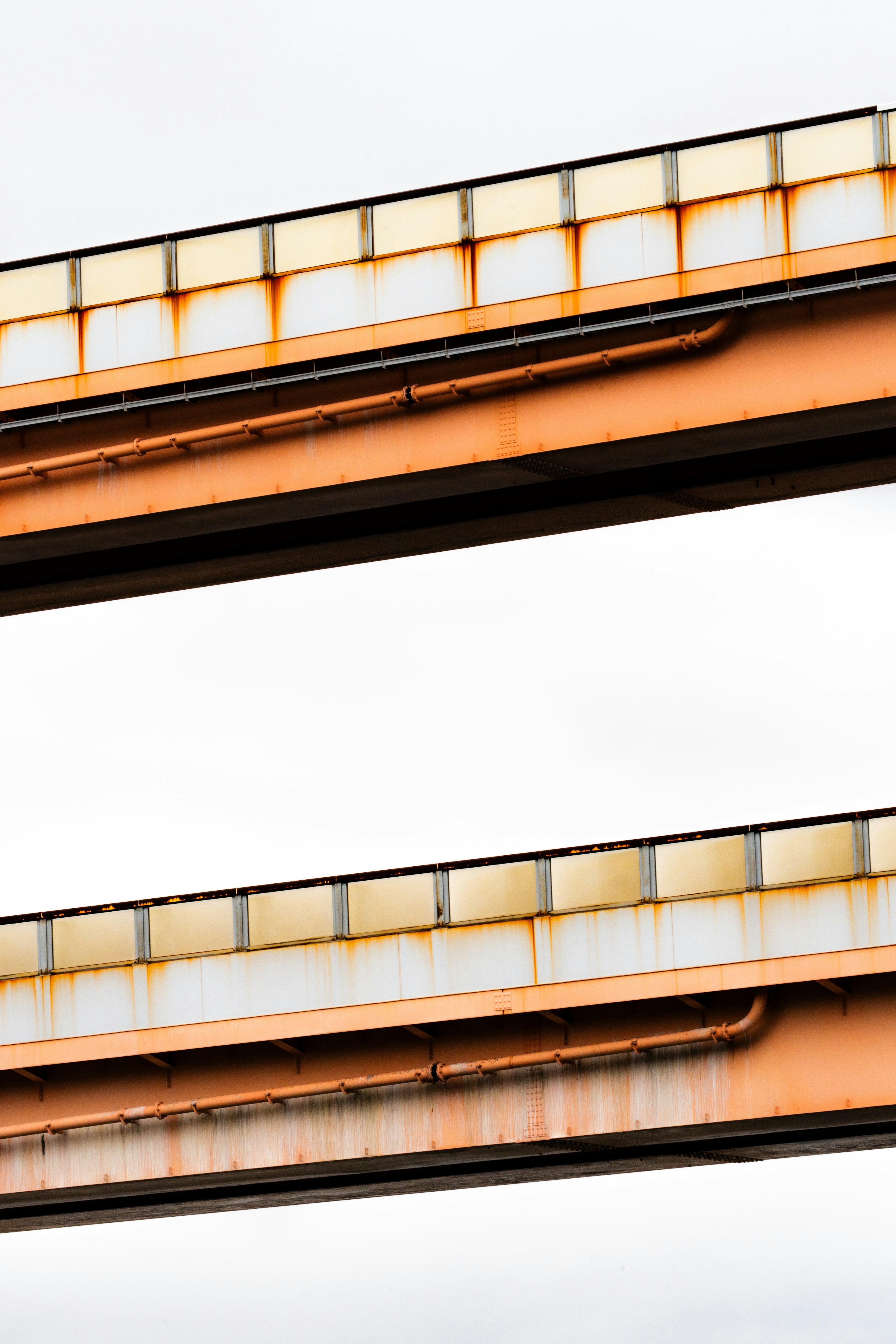 Orange steel beams of a railway bridge against a white background