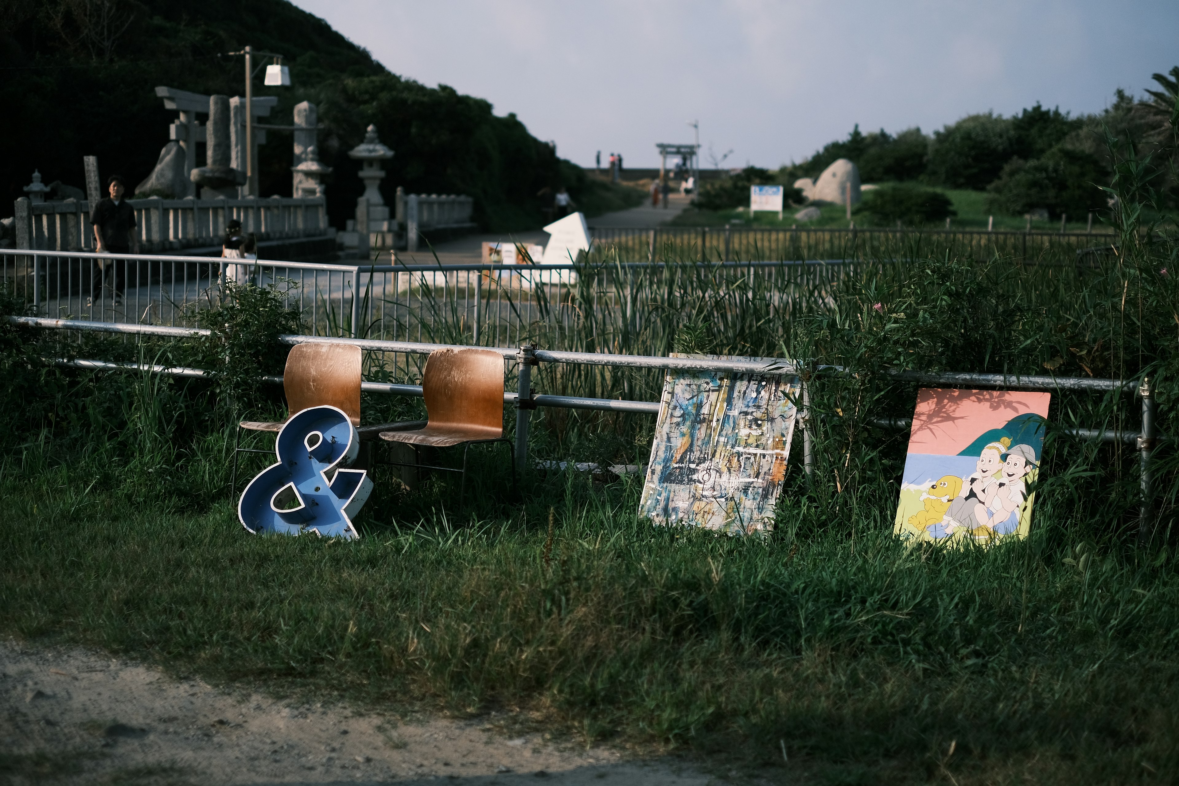 Landschaft mit Stühlen und Kunstwerken im Gras