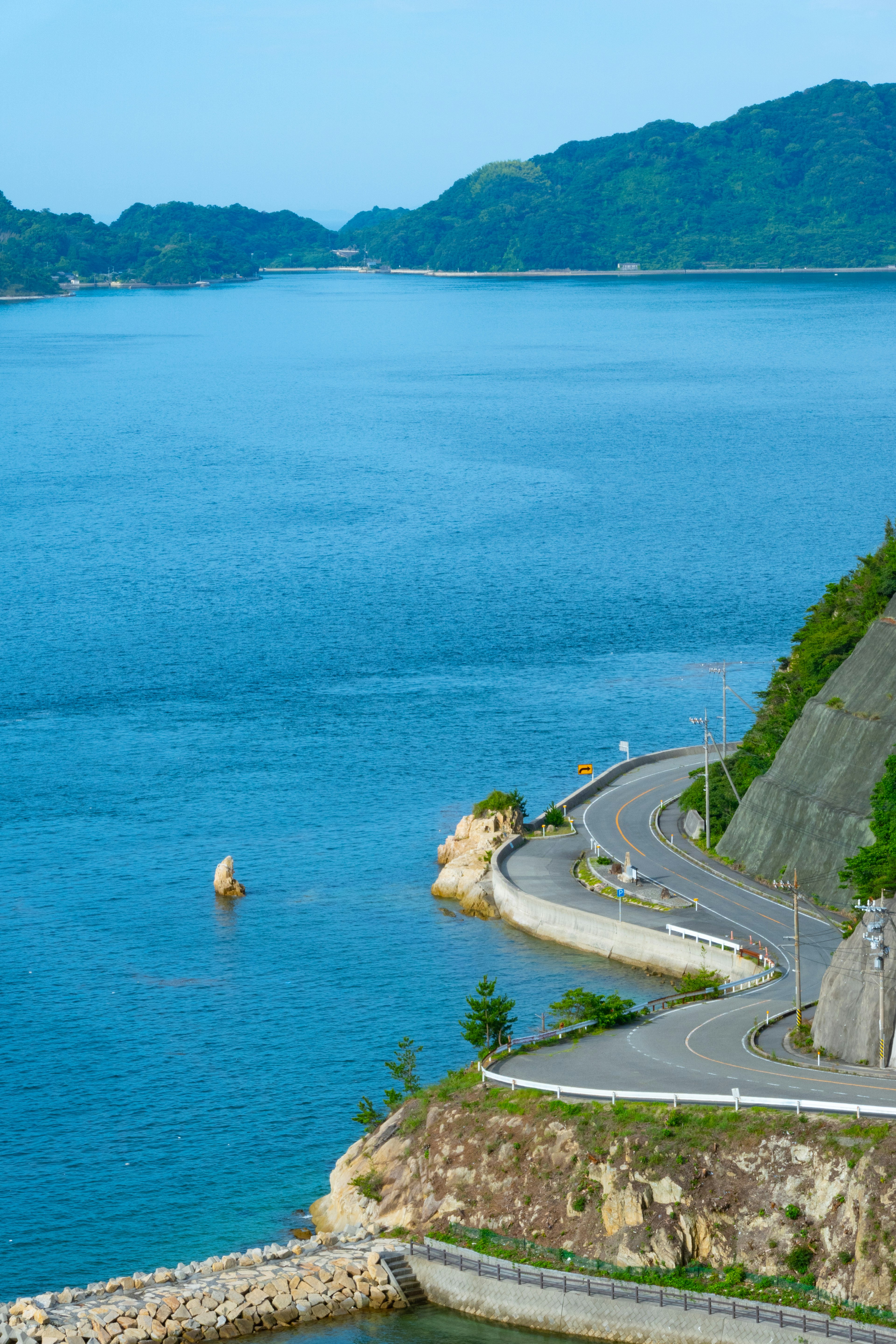 青い海と緑の山々が広がる風景に沿った曲がりくねった道路