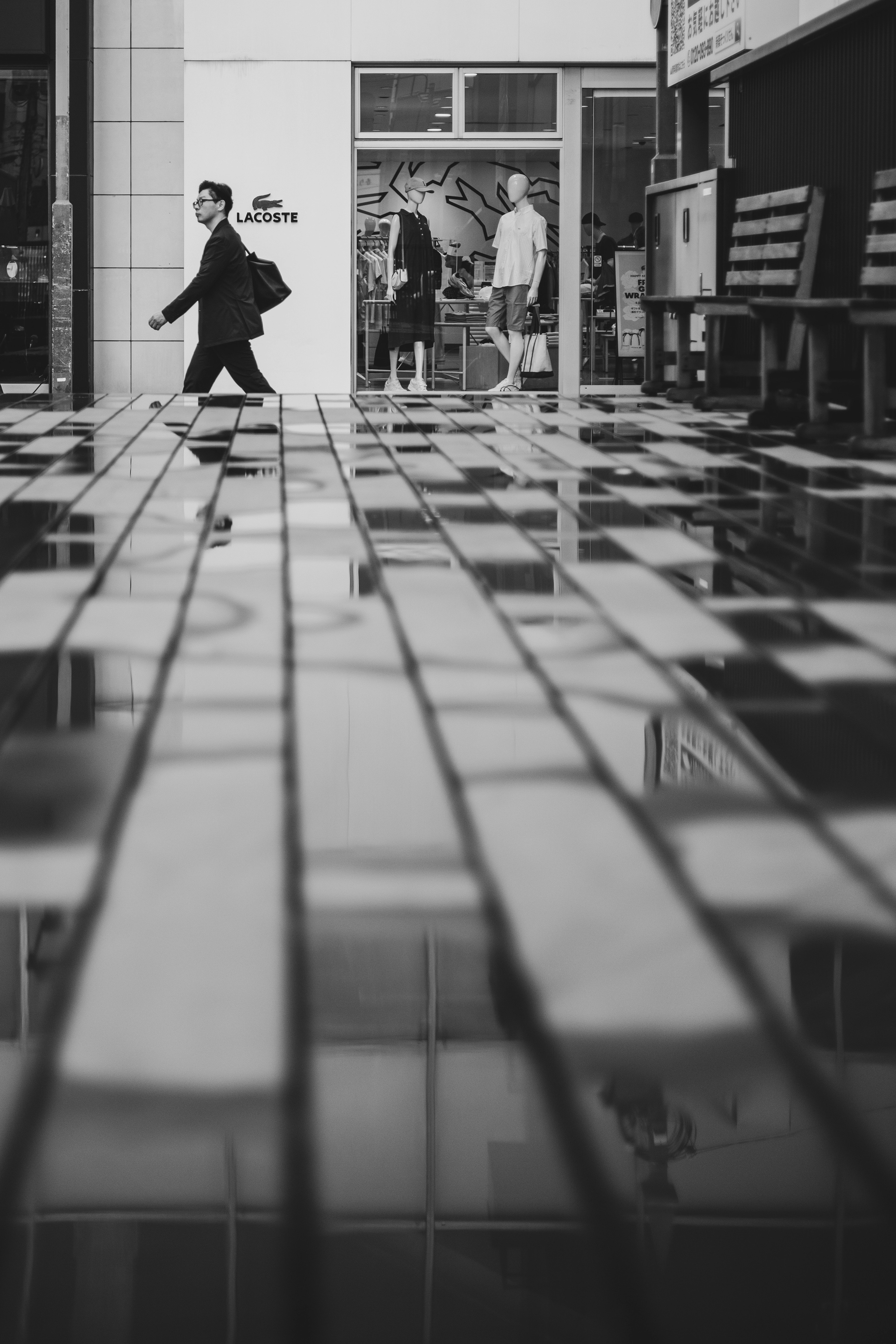 Businessman walking on black and white tiled floor with people in the background