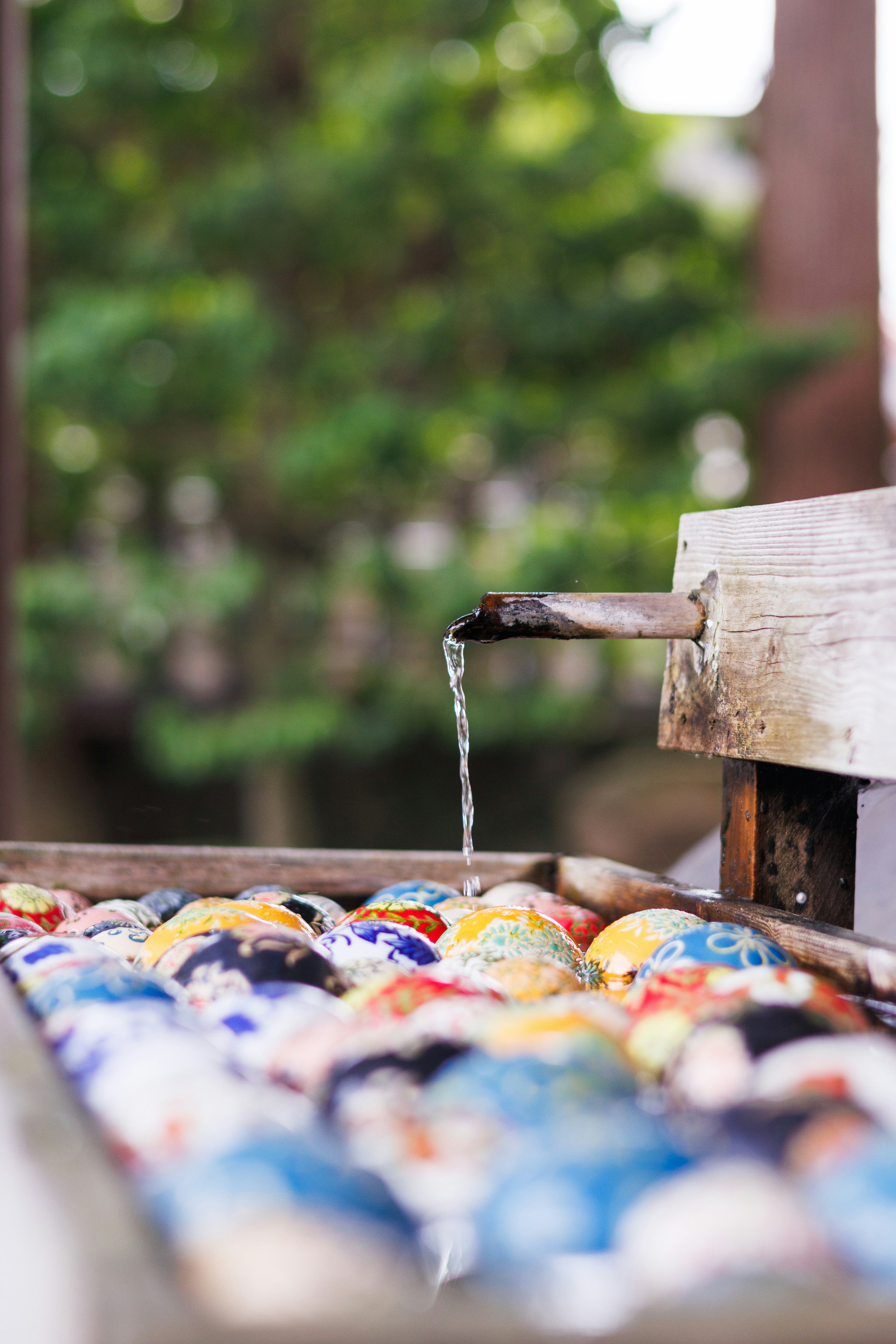 Bassin en bois avec de l'eau qui coule et des boules en céramique colorées