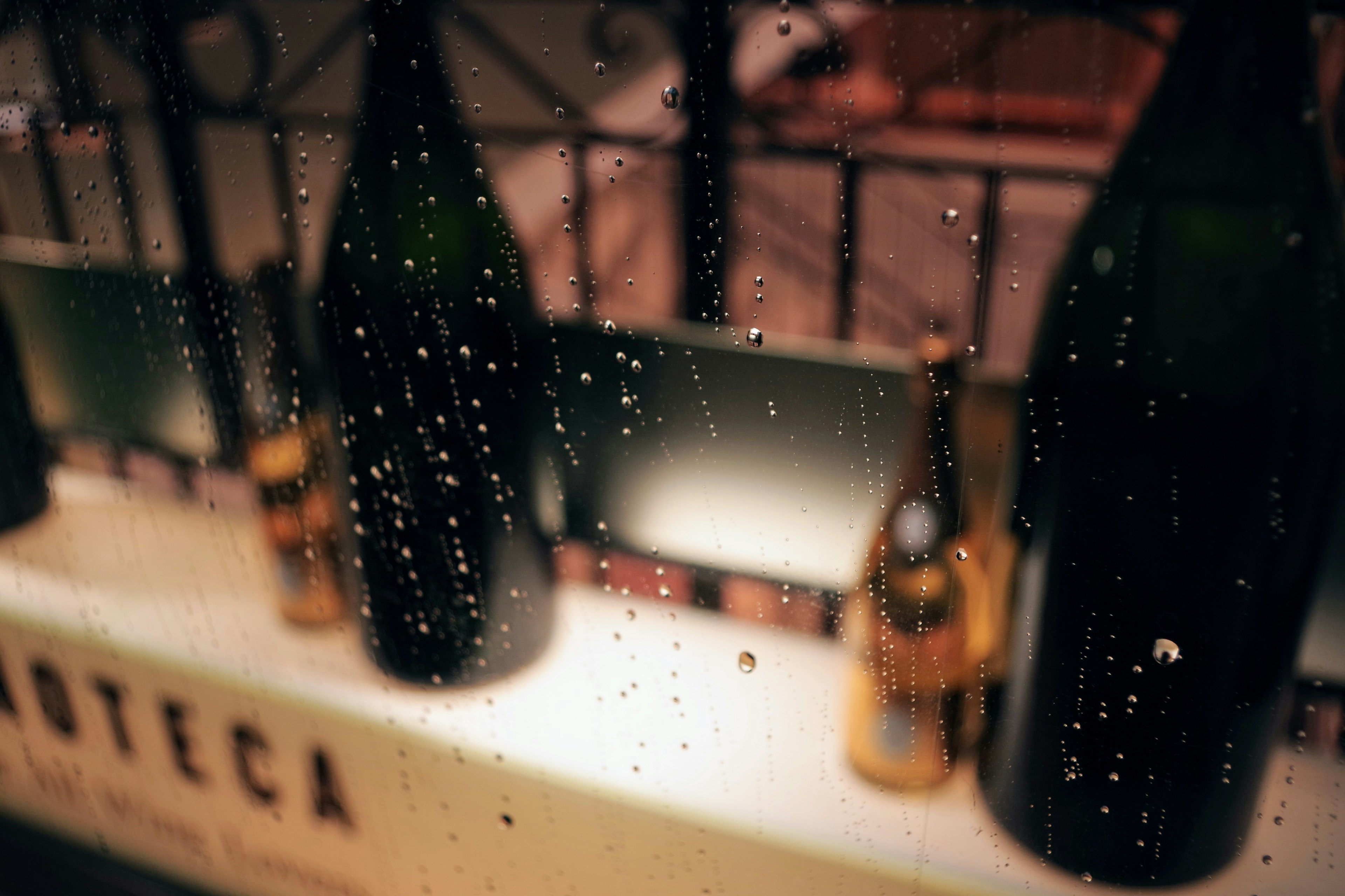 Scene of bottles and raindrops viewed through a window