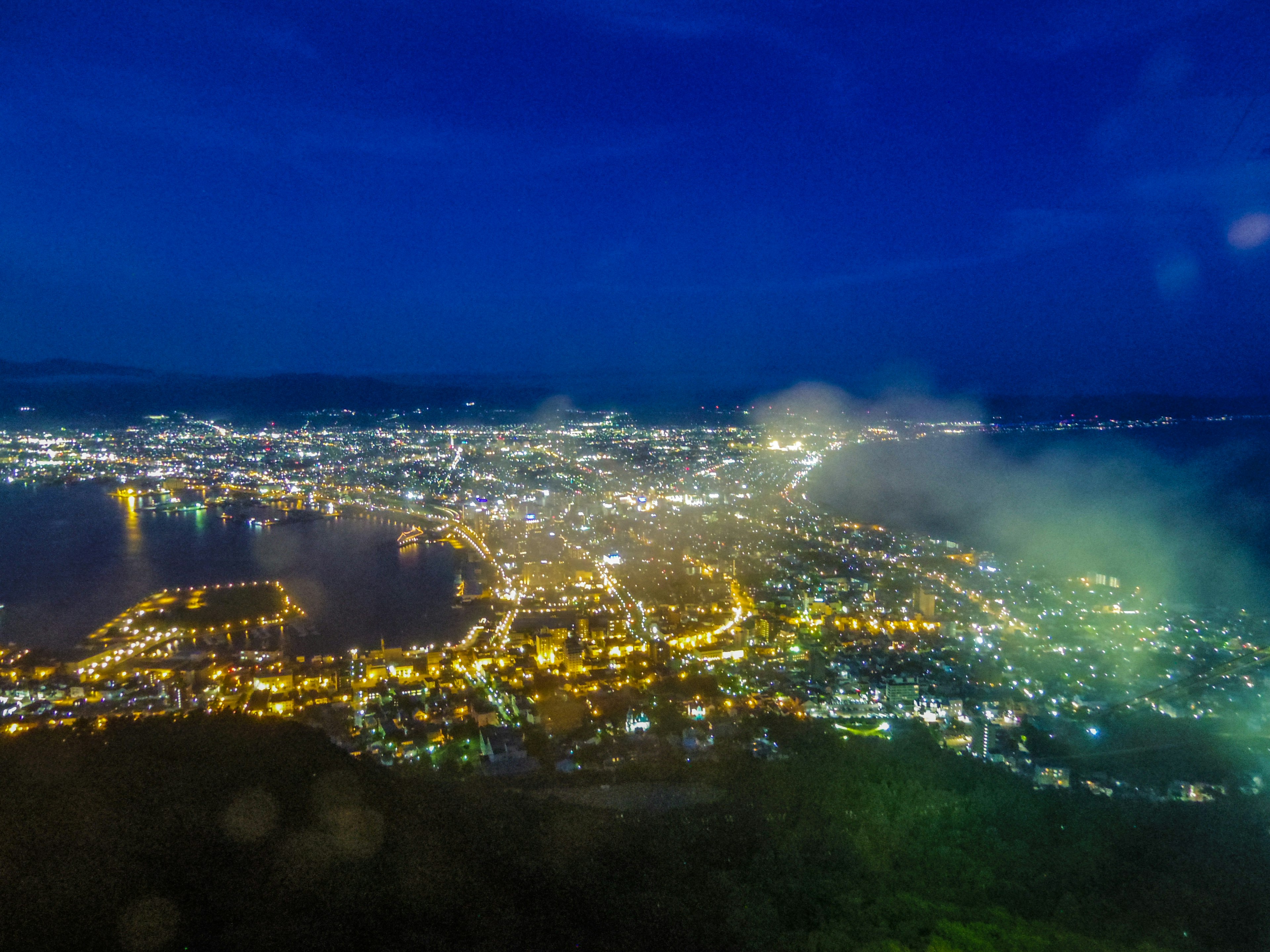 Vue panoramique d'une ville la nuit illuminée par des lumières le long du port