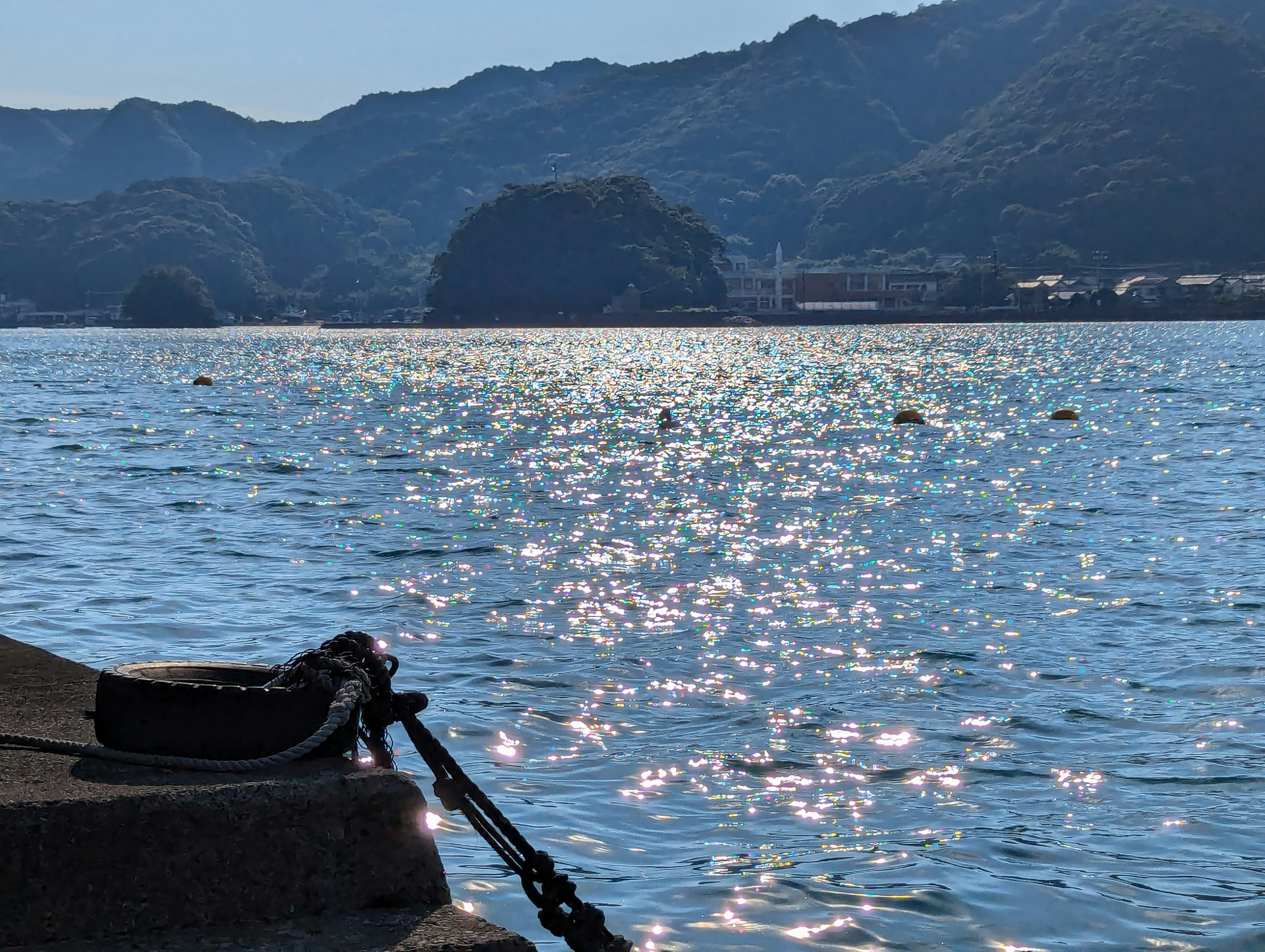 Mare calmo e paesaggio montano con superficie d'acqua scintillante e corda della barca