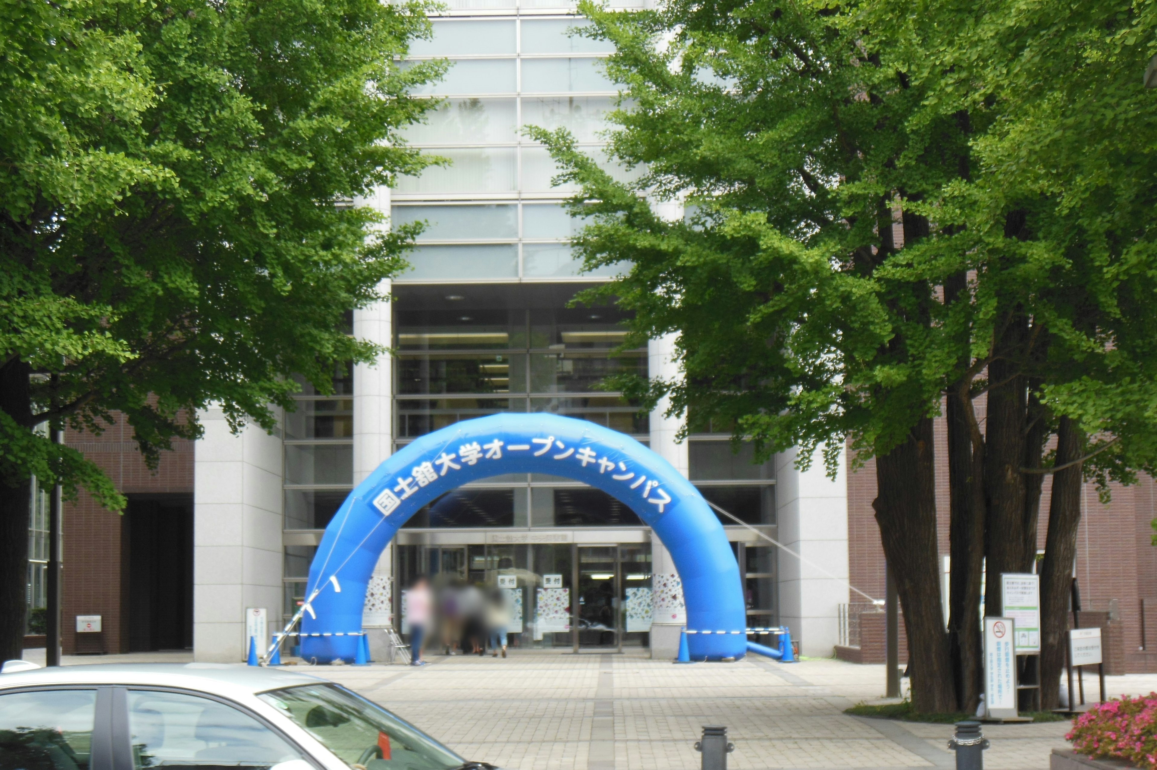 Entrance of a building featuring a blue archway surrounded by green trees