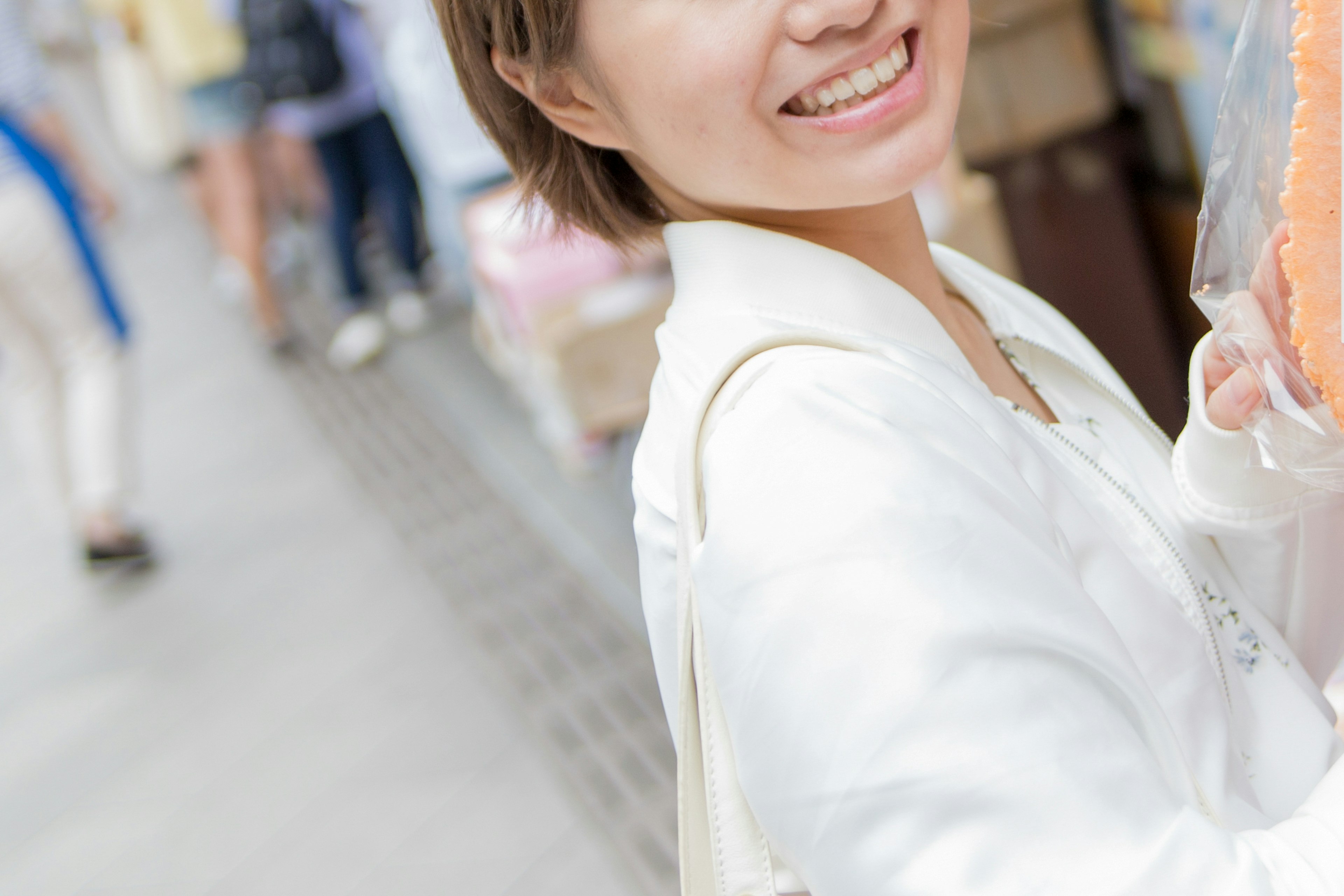 Une femme souriante en veste légère s'amusant dans la rue