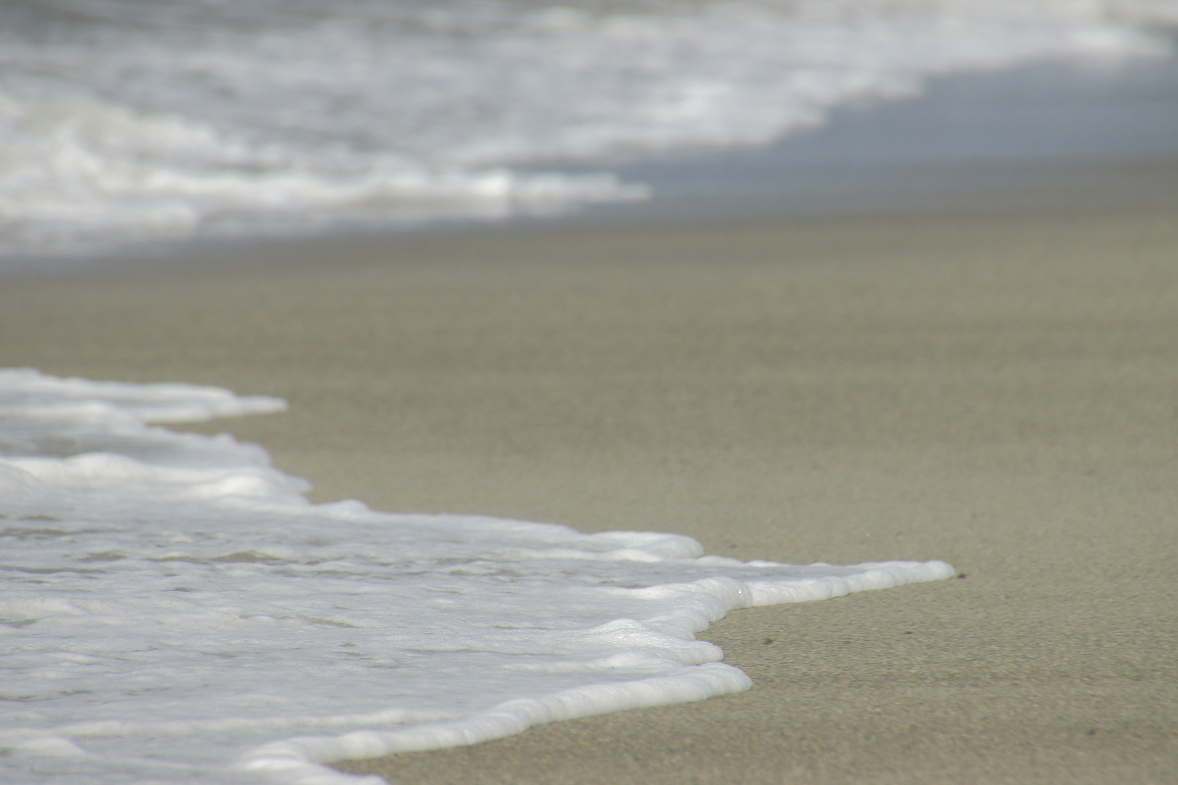 Wellen, die sanft an einen Sandstrand schlagen